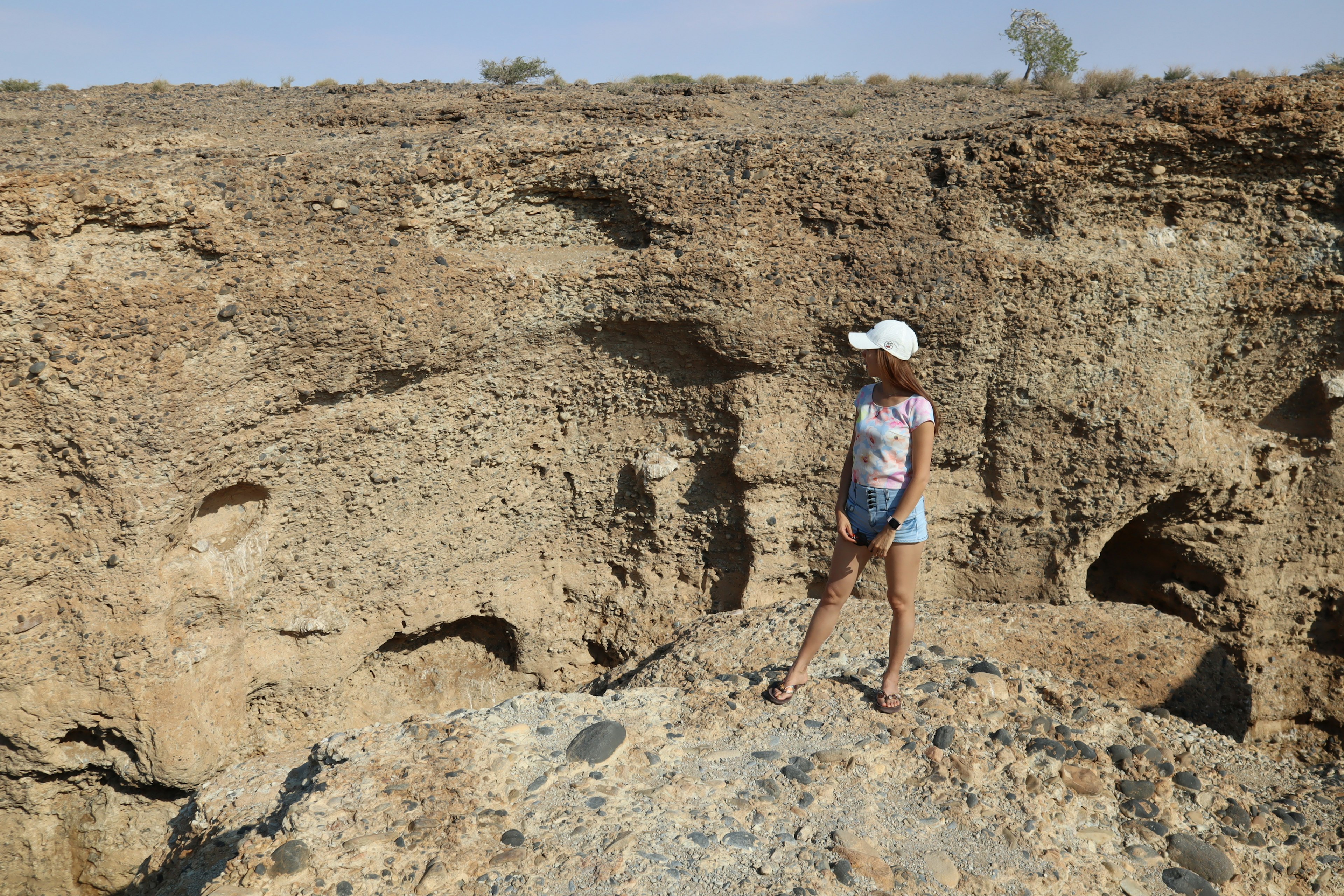 A young girl standing on a rocky ledge in a rugged landscape