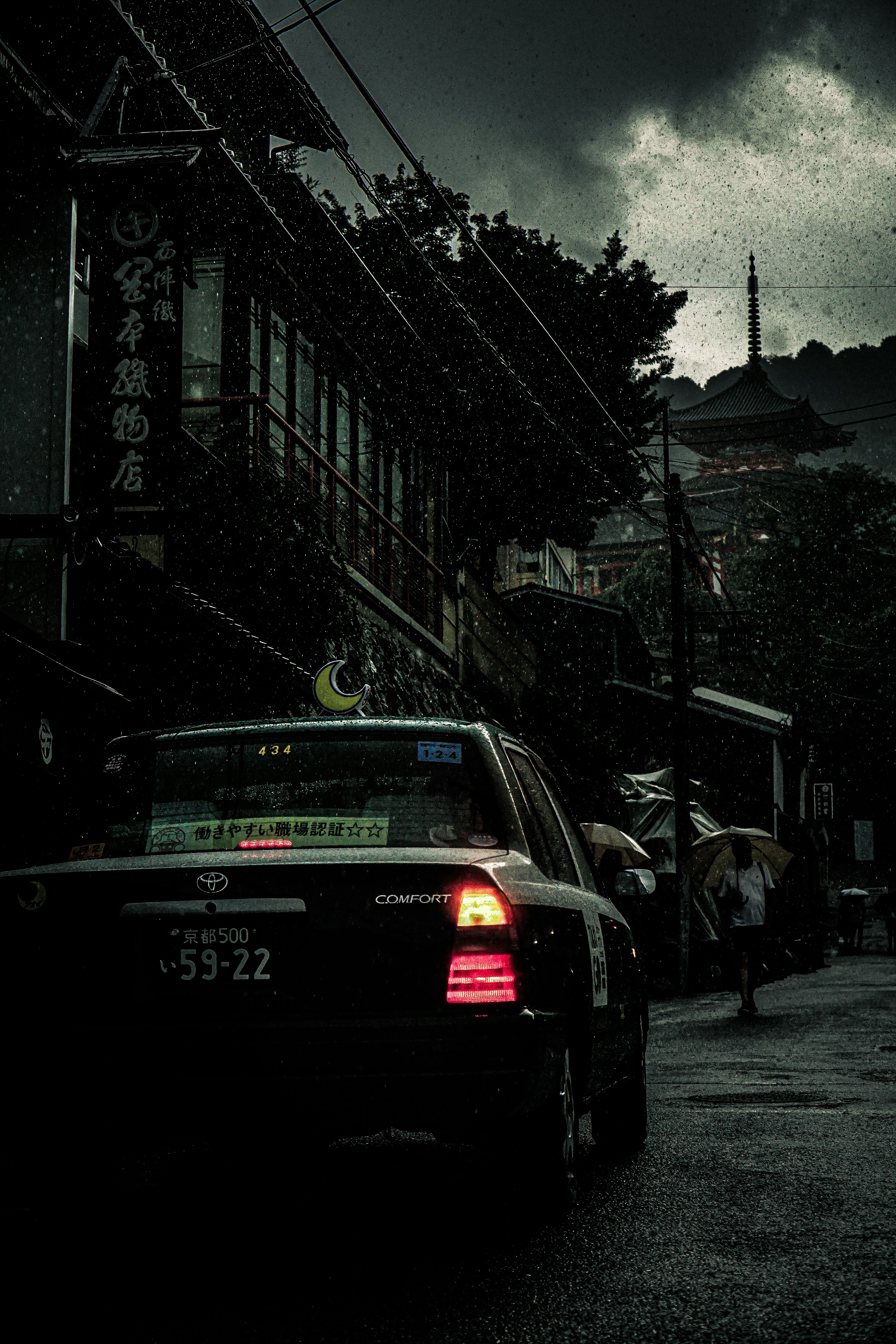 暗い空の下に停まっているタクシーと雨に濡れた街の風景