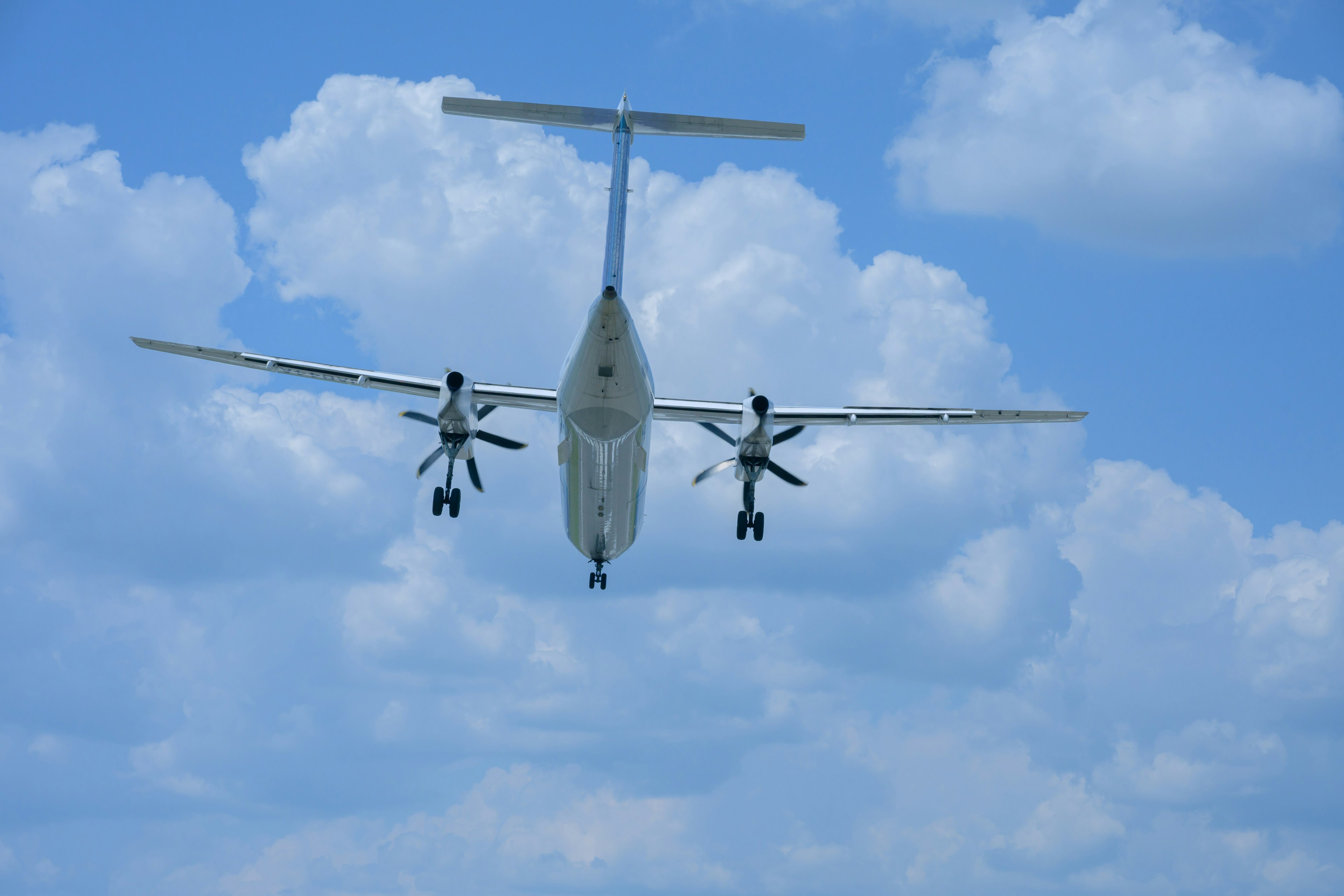 Twin-engine propeller aircraft flying against a blue sky