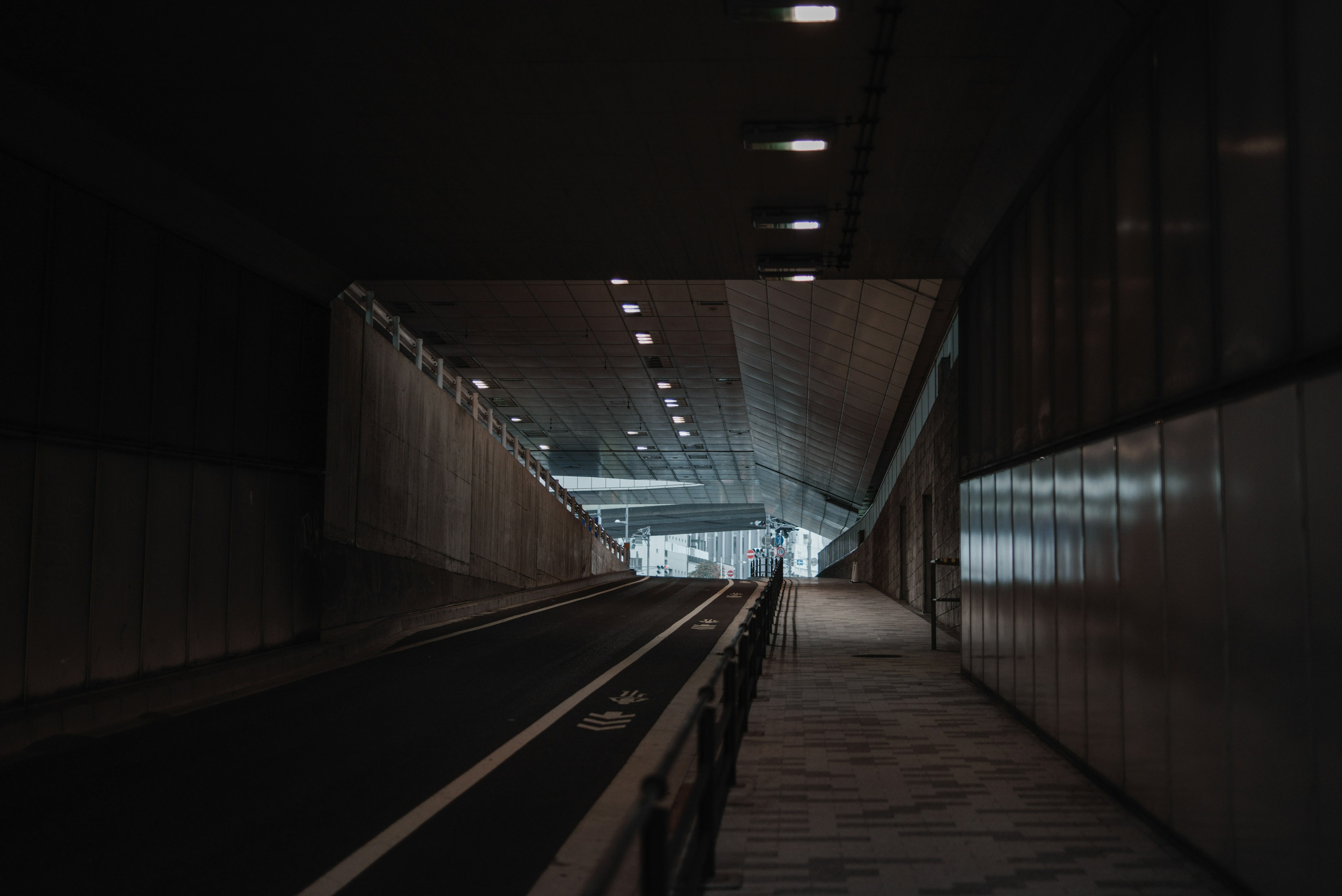 Tunnel poco illuminato con marciapiede e strada