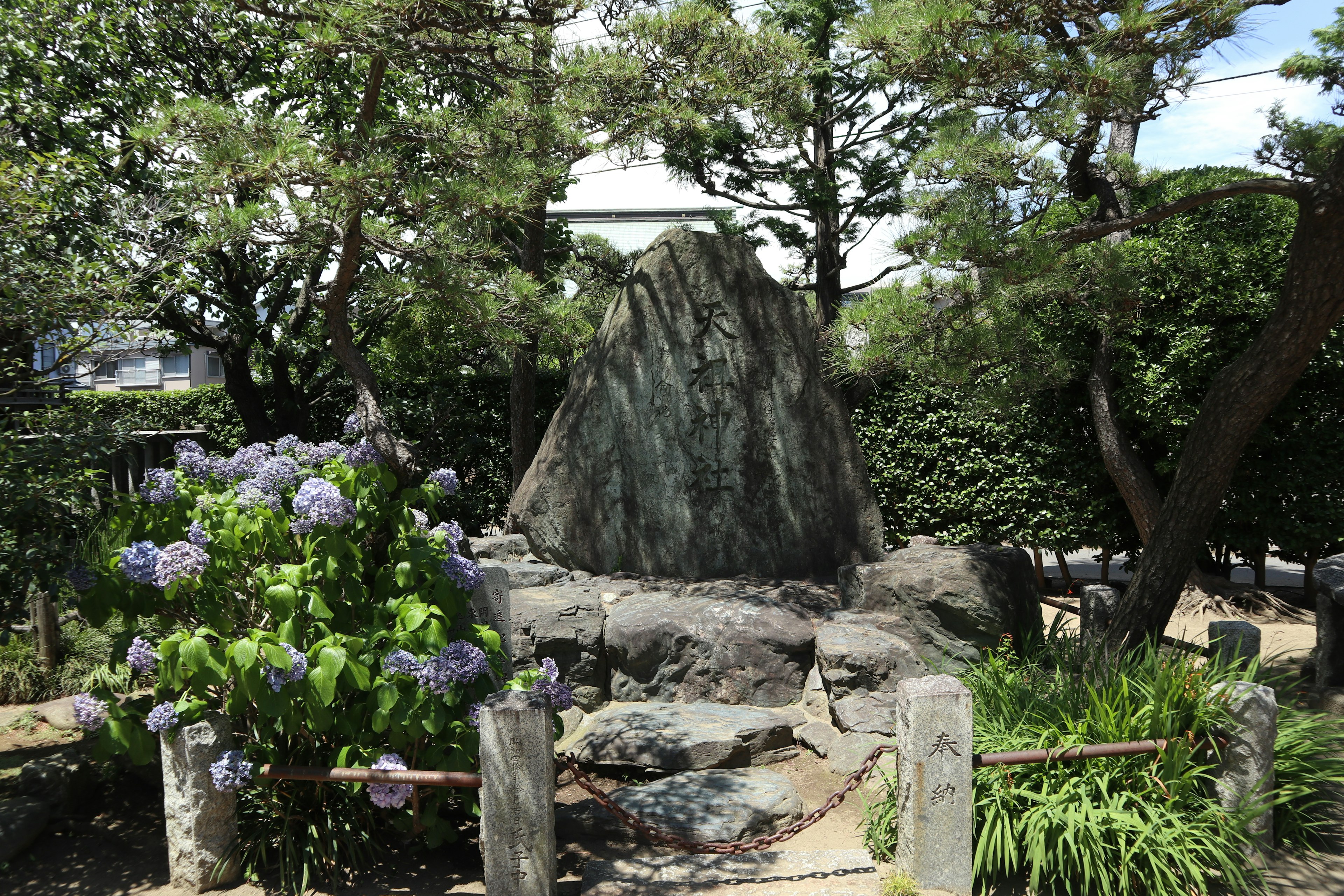 風景如畫的日本花園，中央有一塊大石頭，四周環繞著綠色植物和花卉