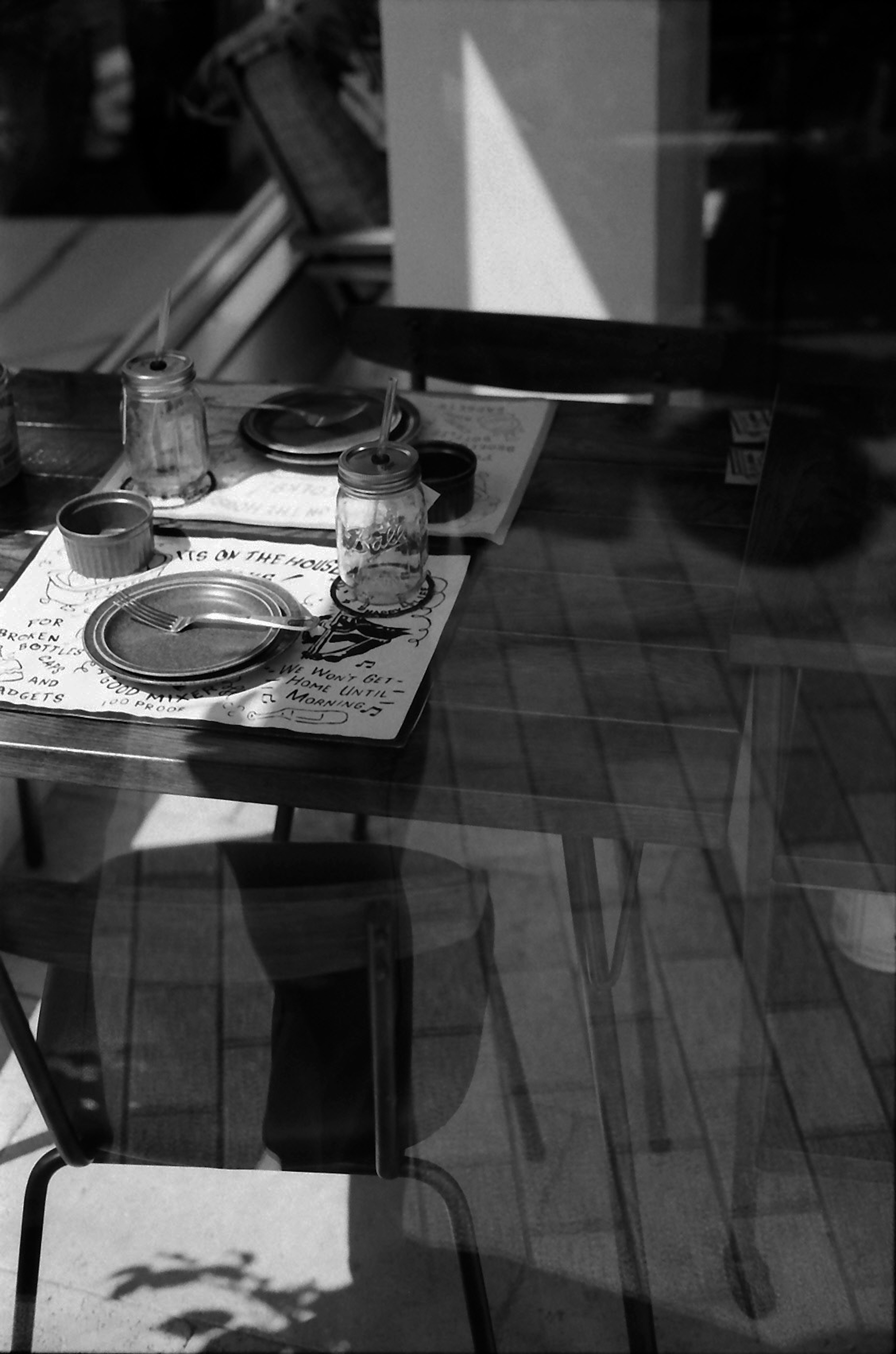 Foto en blanco y negro de una mesa de vidrio con platos y tazas