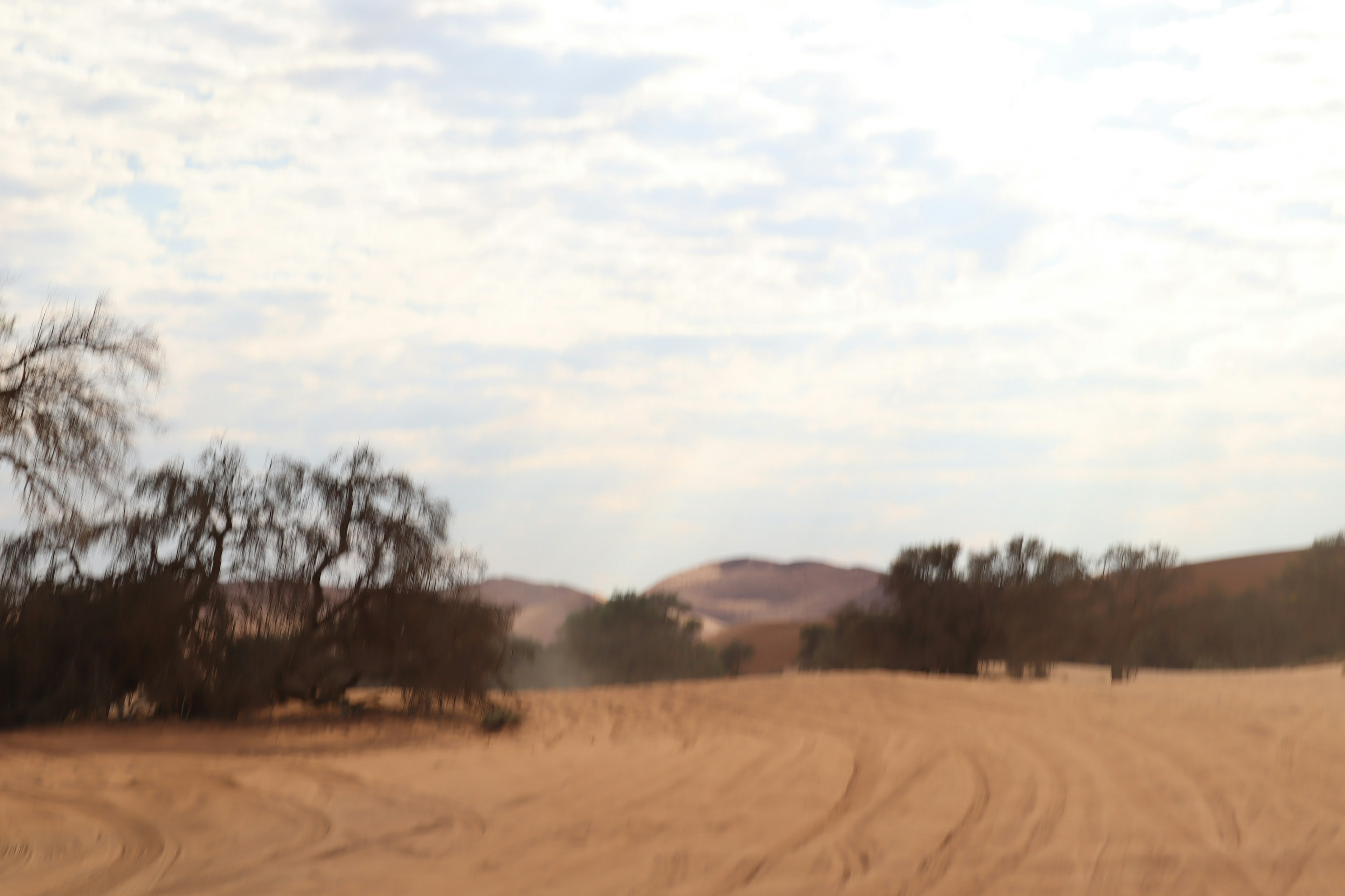 Desert landscape featuring rolling sand dunes and a cloudy sky