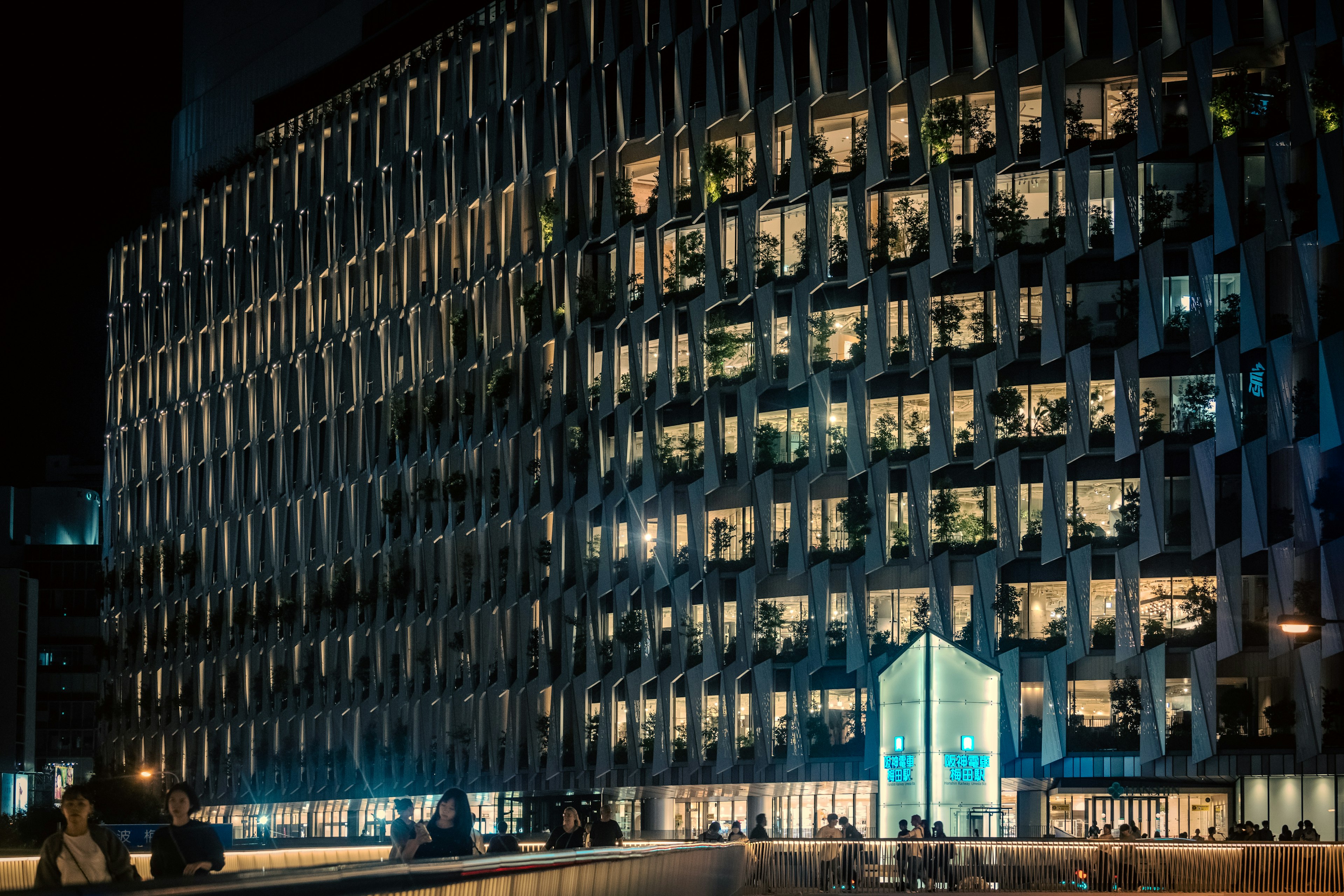 Façade moderne d'un bâtiment la nuit avec des fenêtres illuminées et un design unique