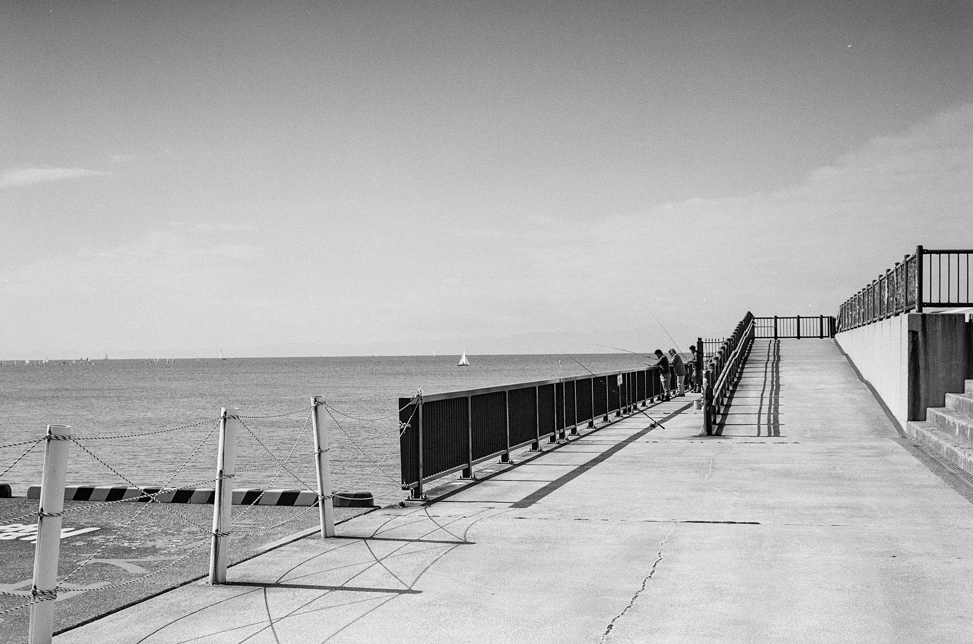 Molo in cemento che porta al mare con una recinzione