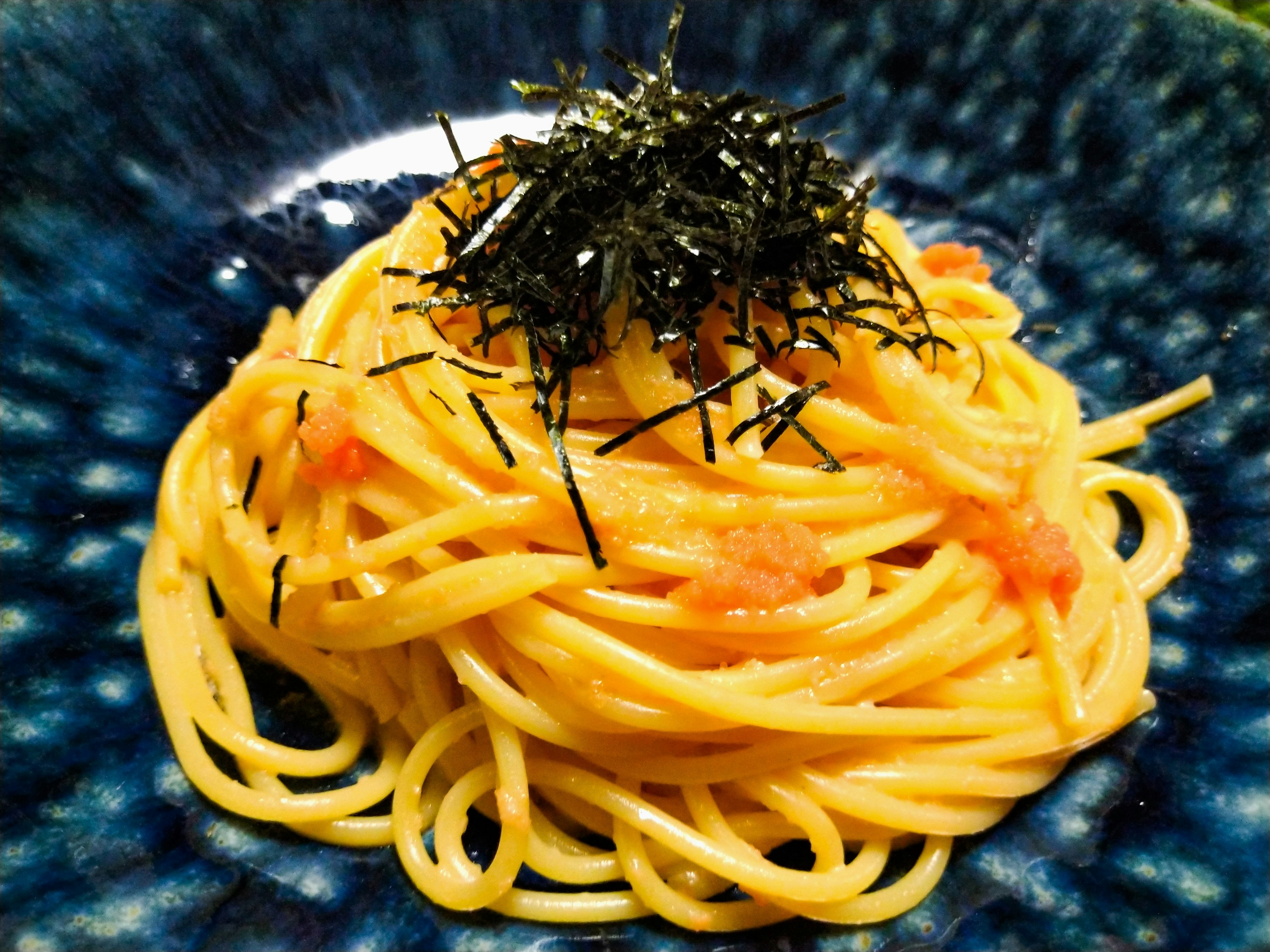 Spaghetti mit Algen auf einem blauen Teller serviert