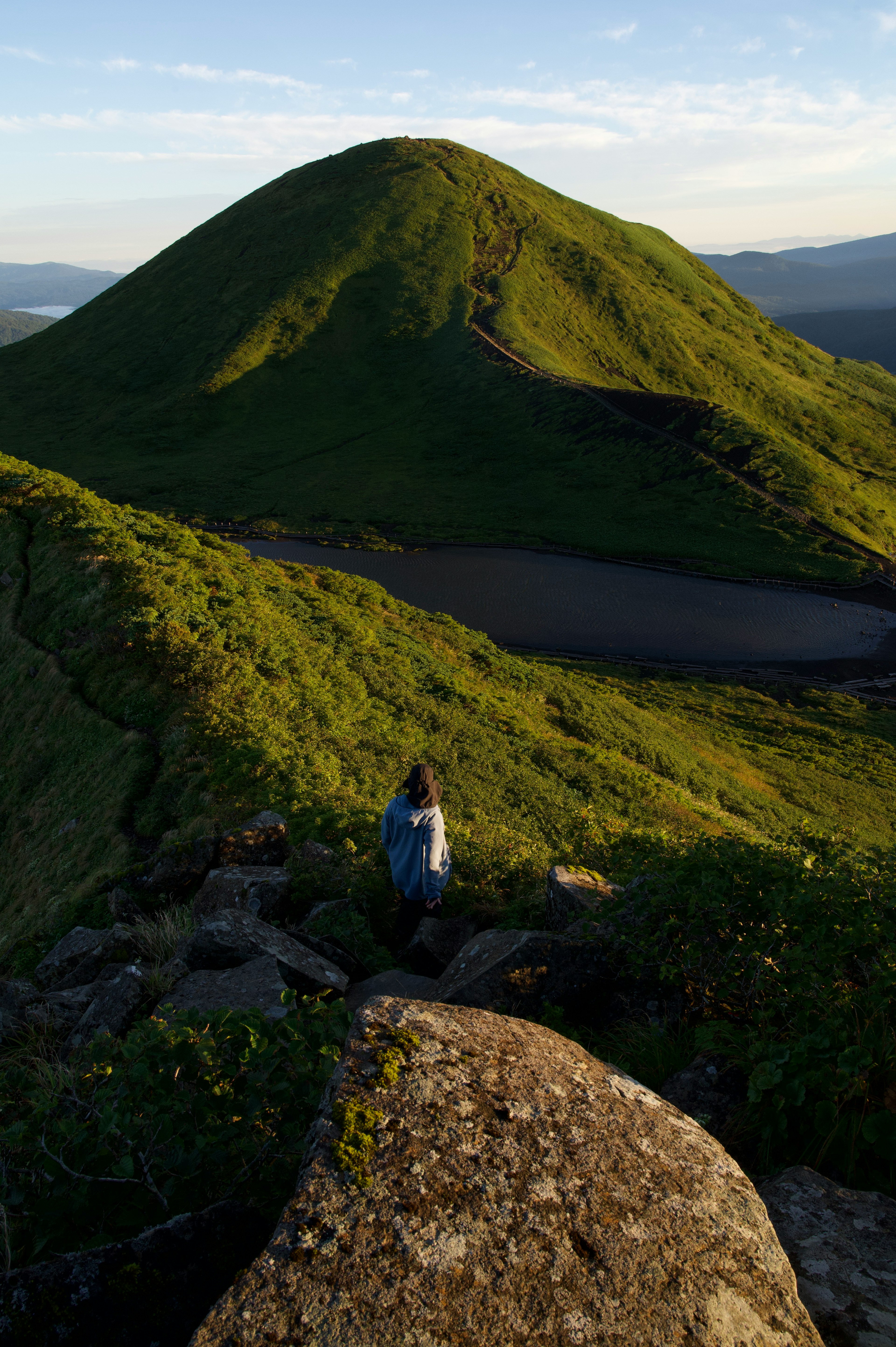 緑の丘と湖を見渡す登山者の風景