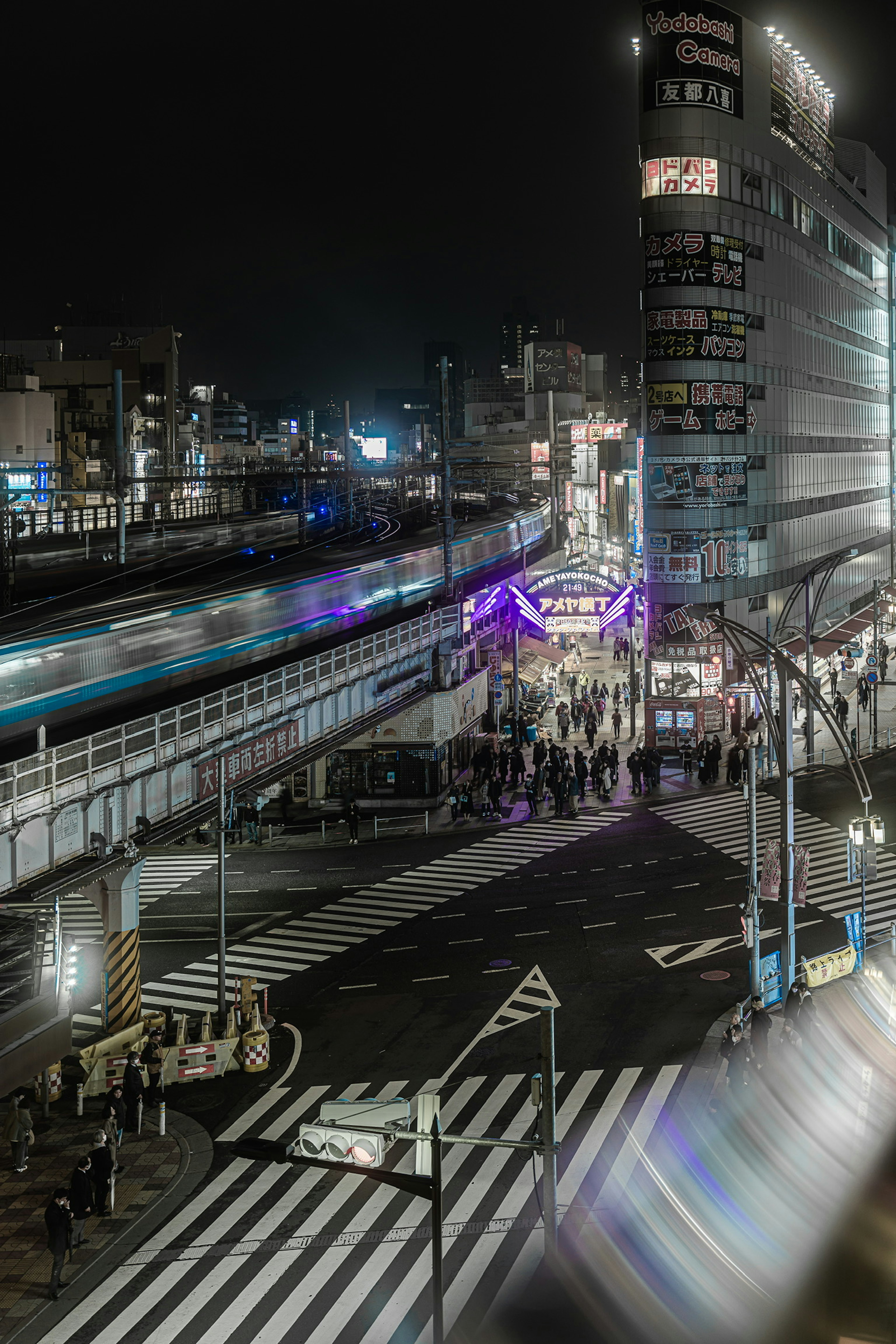 Paesaggio urbano notturno con persone e strade treno e edifici visibili