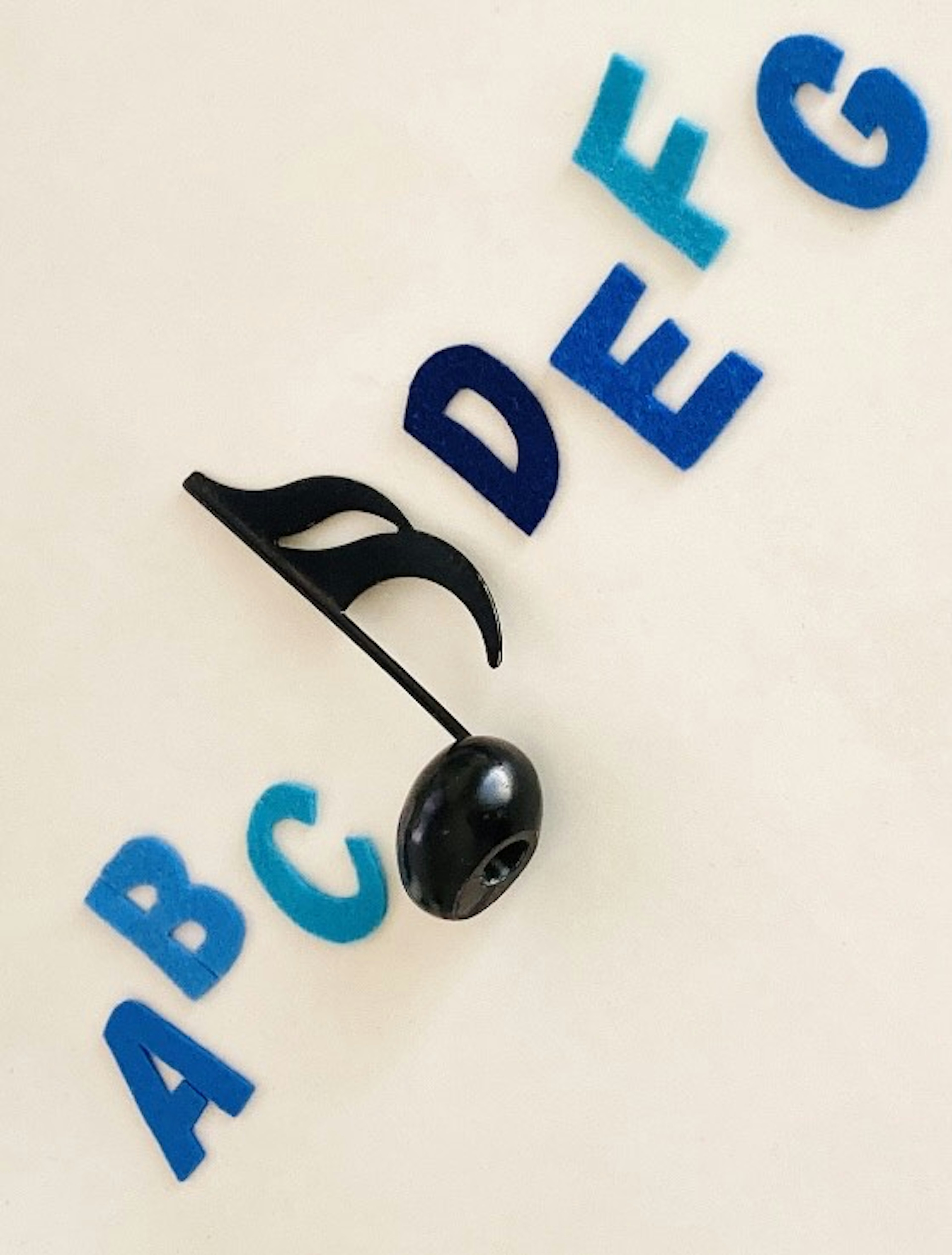 Black musical note surrounded by colorful alphabet letters A B C D E F G