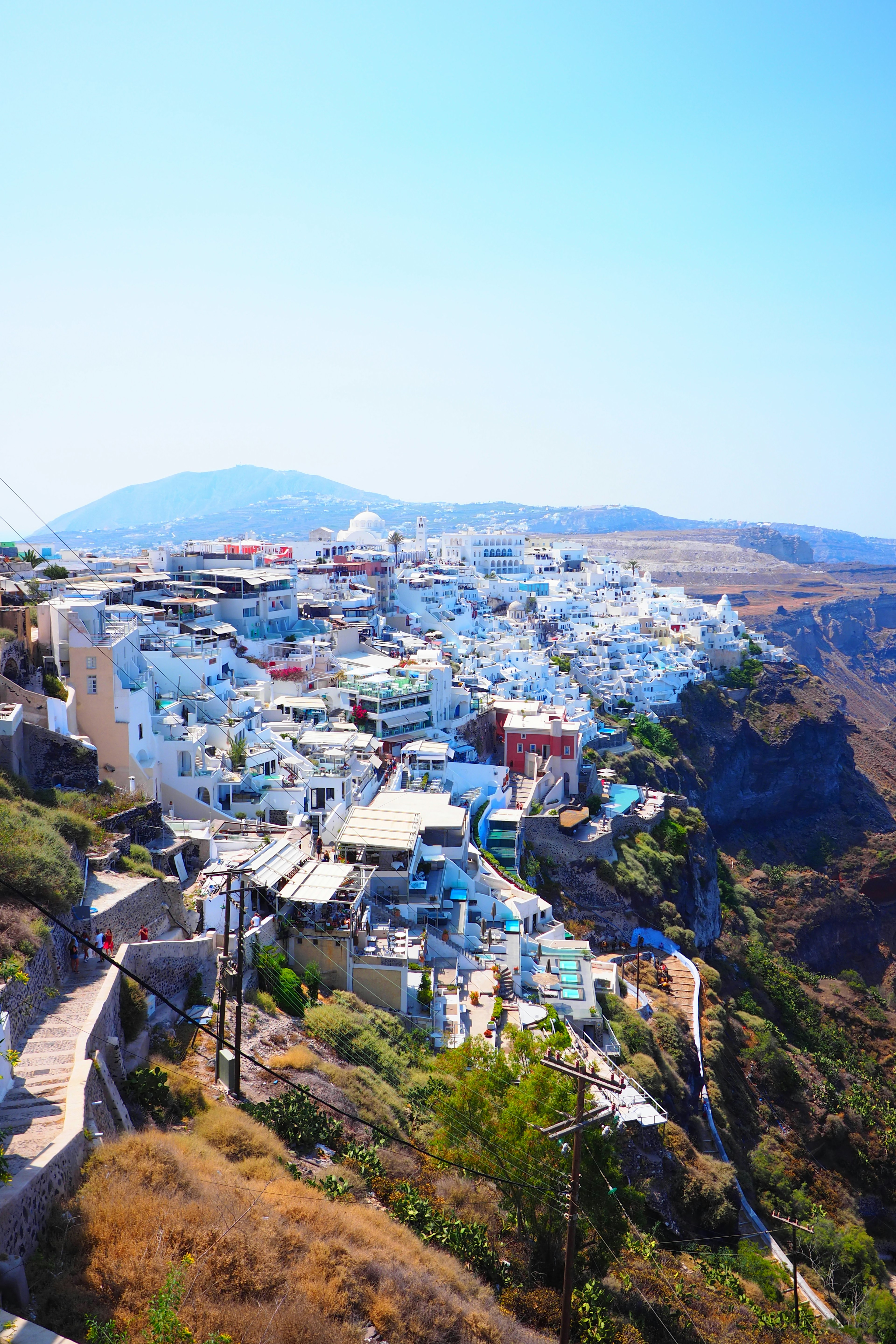 Eine atemberaubende Aussicht auf weiße Gebäude in Santorin vor einem klaren blauen Himmel