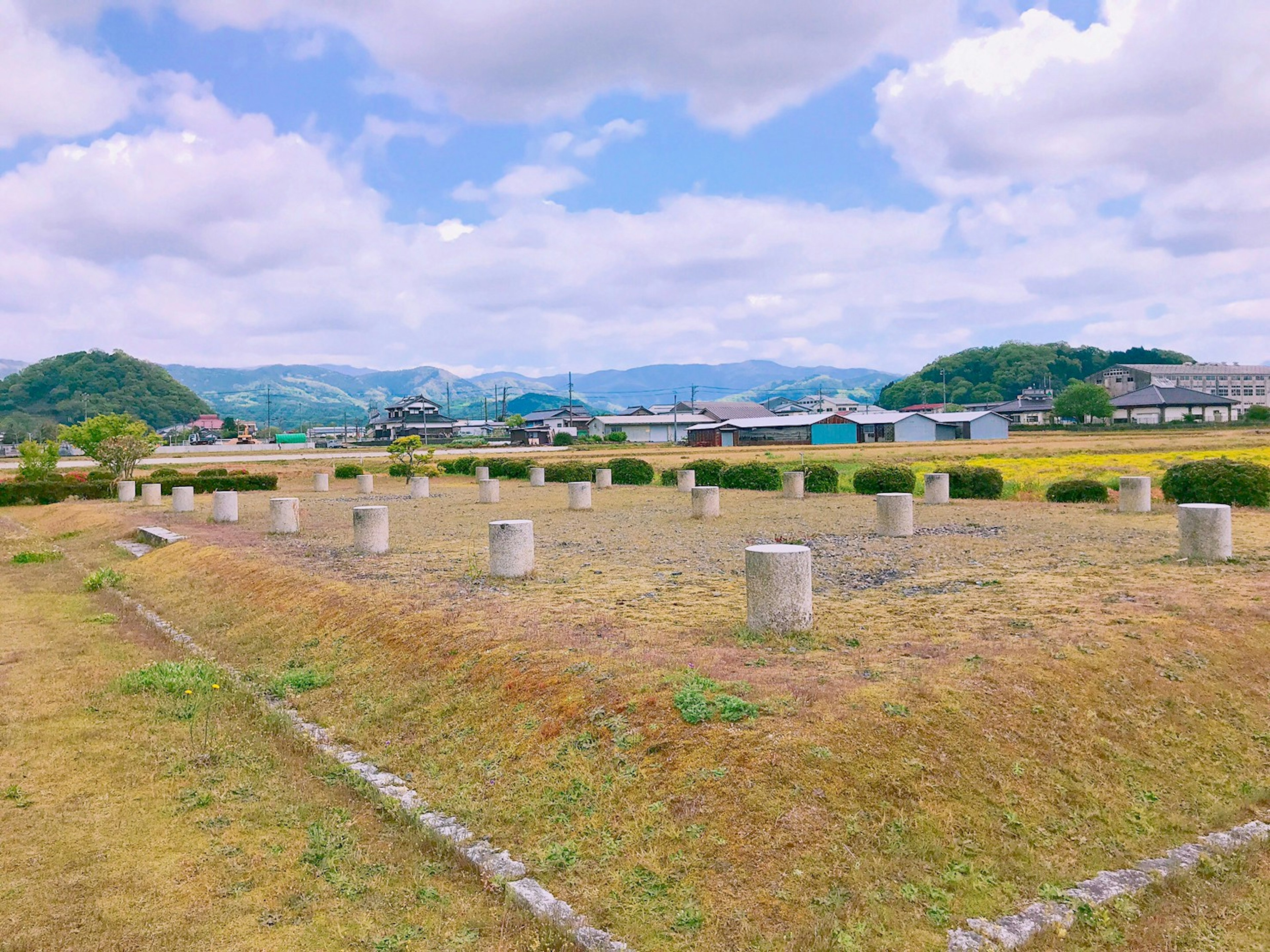 Wide grassy field with stone pillars and blue sky