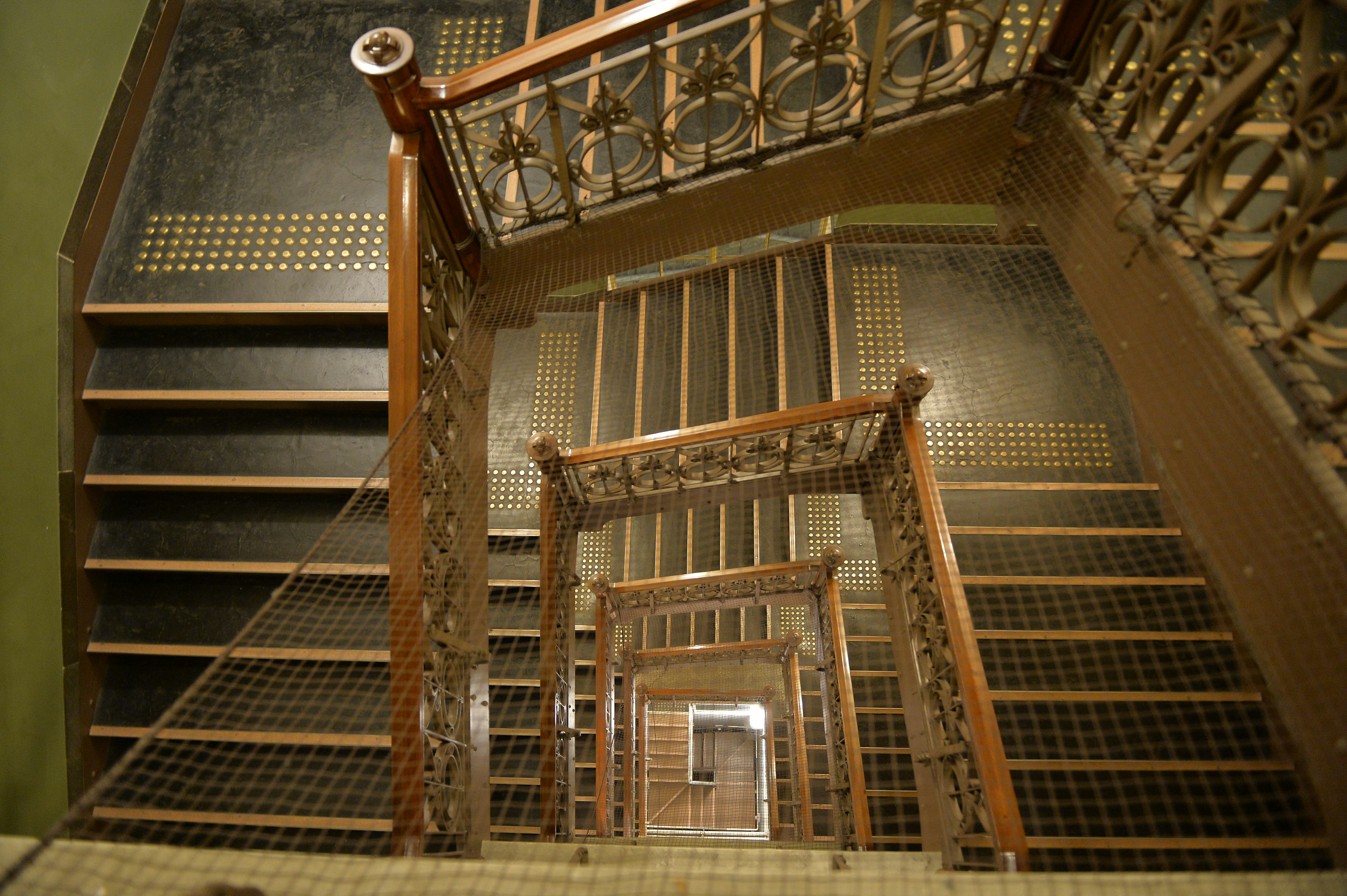 Vue du haut d'un escalier avec rambarde décorative et marches en bois