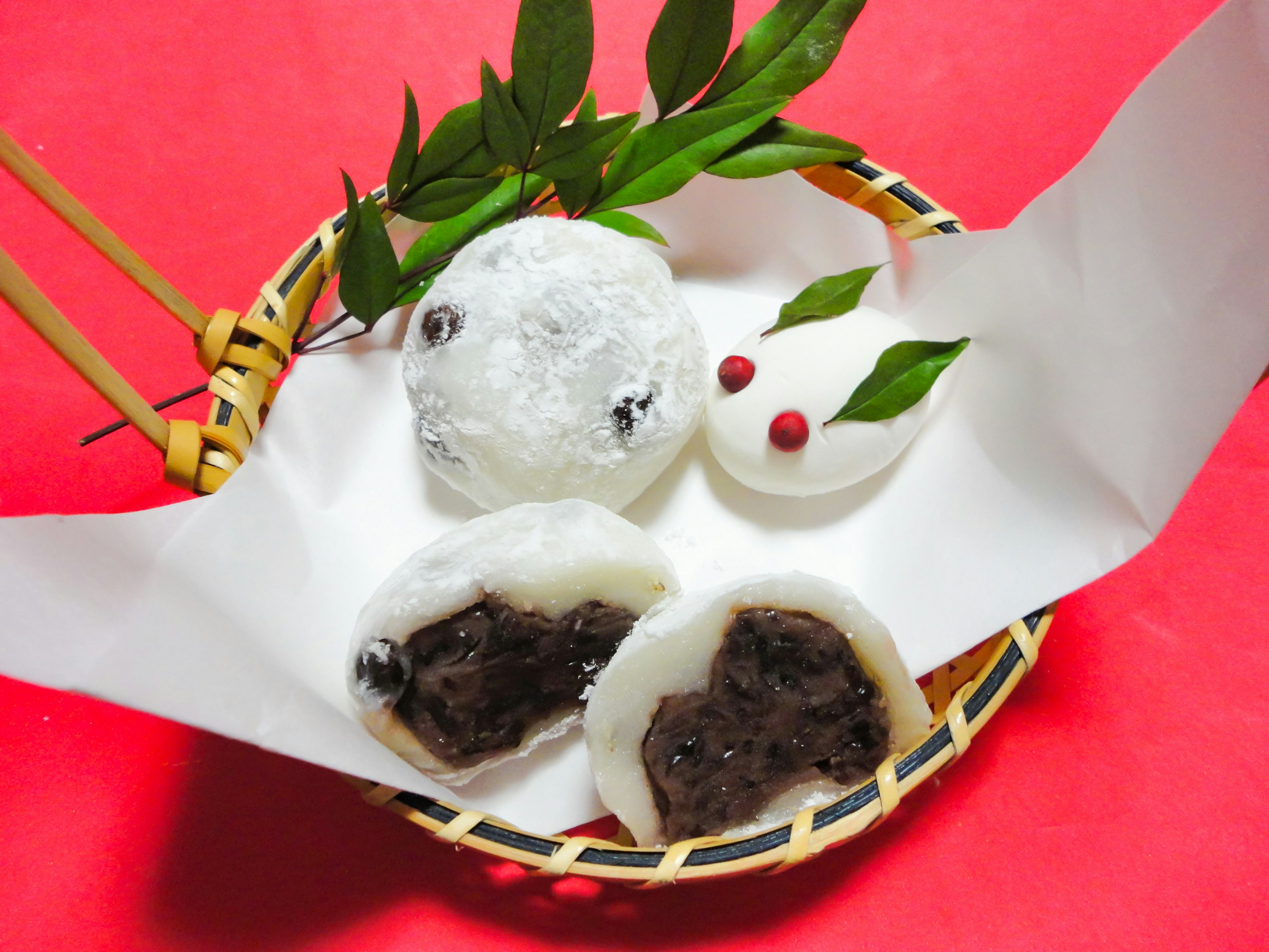 Assorted Japanese sweets featuring mochi with red bean filling on a red background