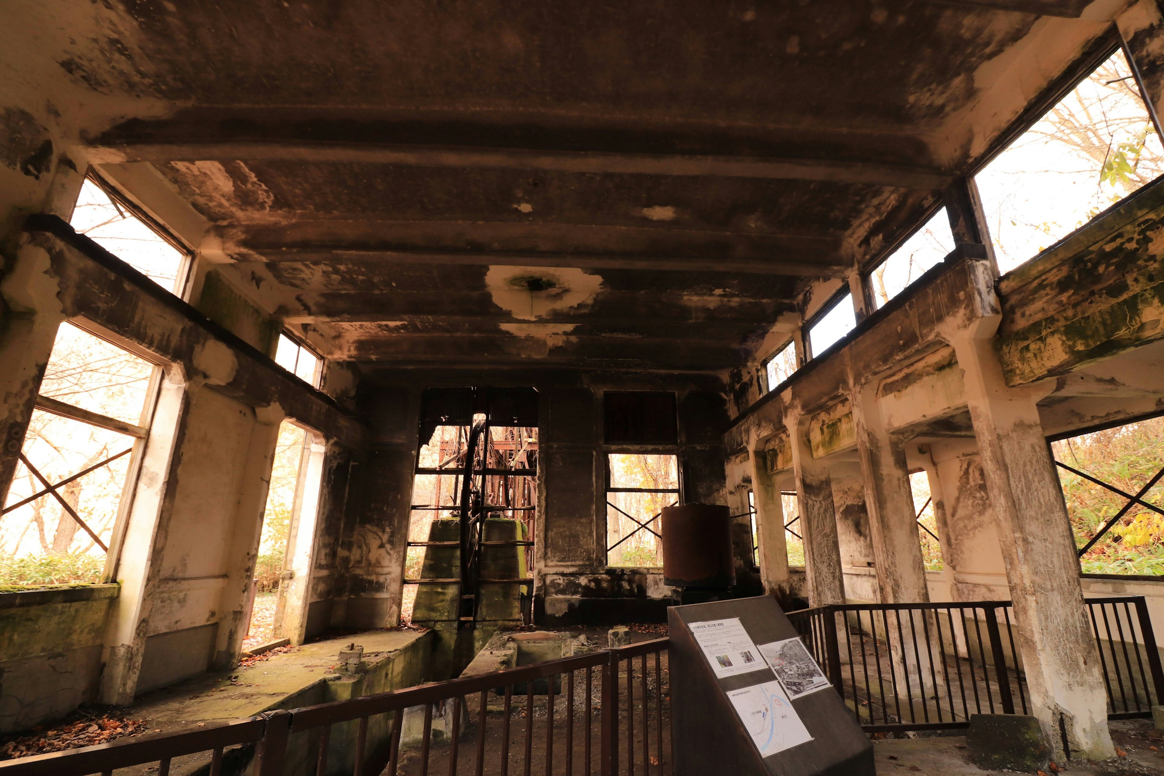 Interior of a dilapidated building with rusted machinery and peeling walls