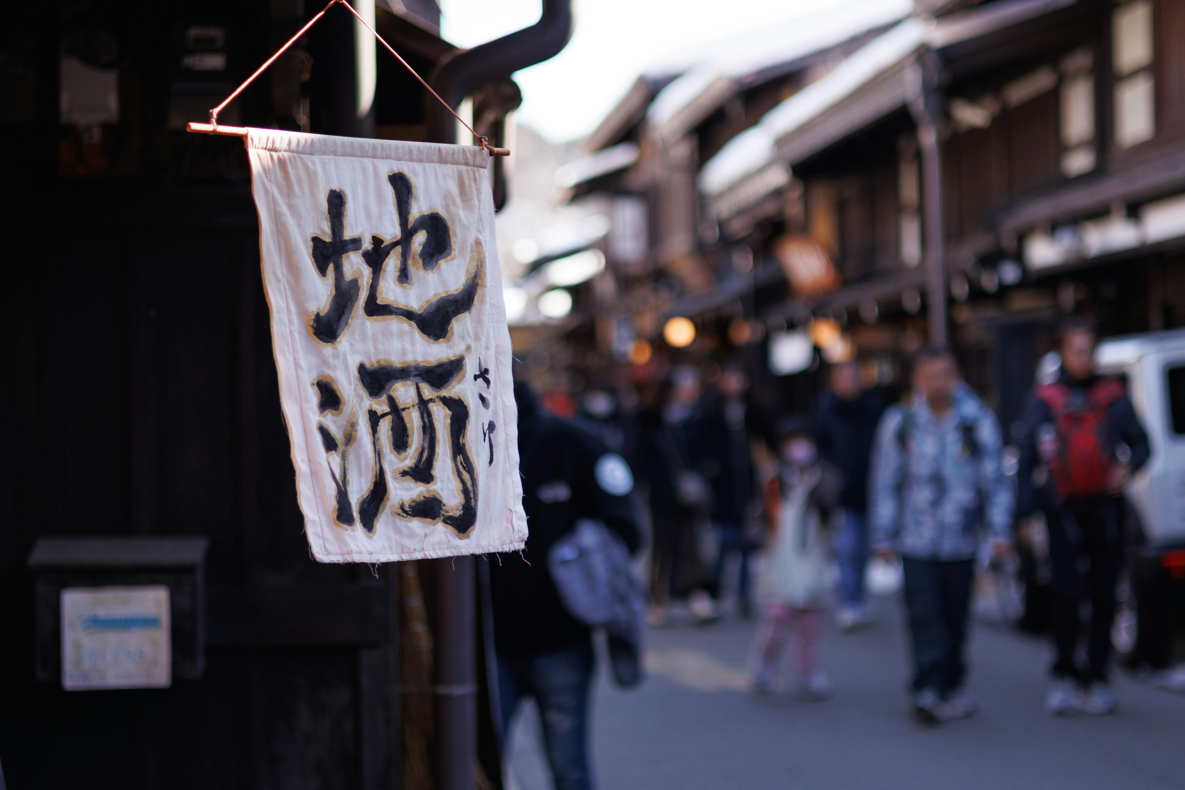 Ein Sake-Shop-Schild in einer alten belebten Straße mit Menschen