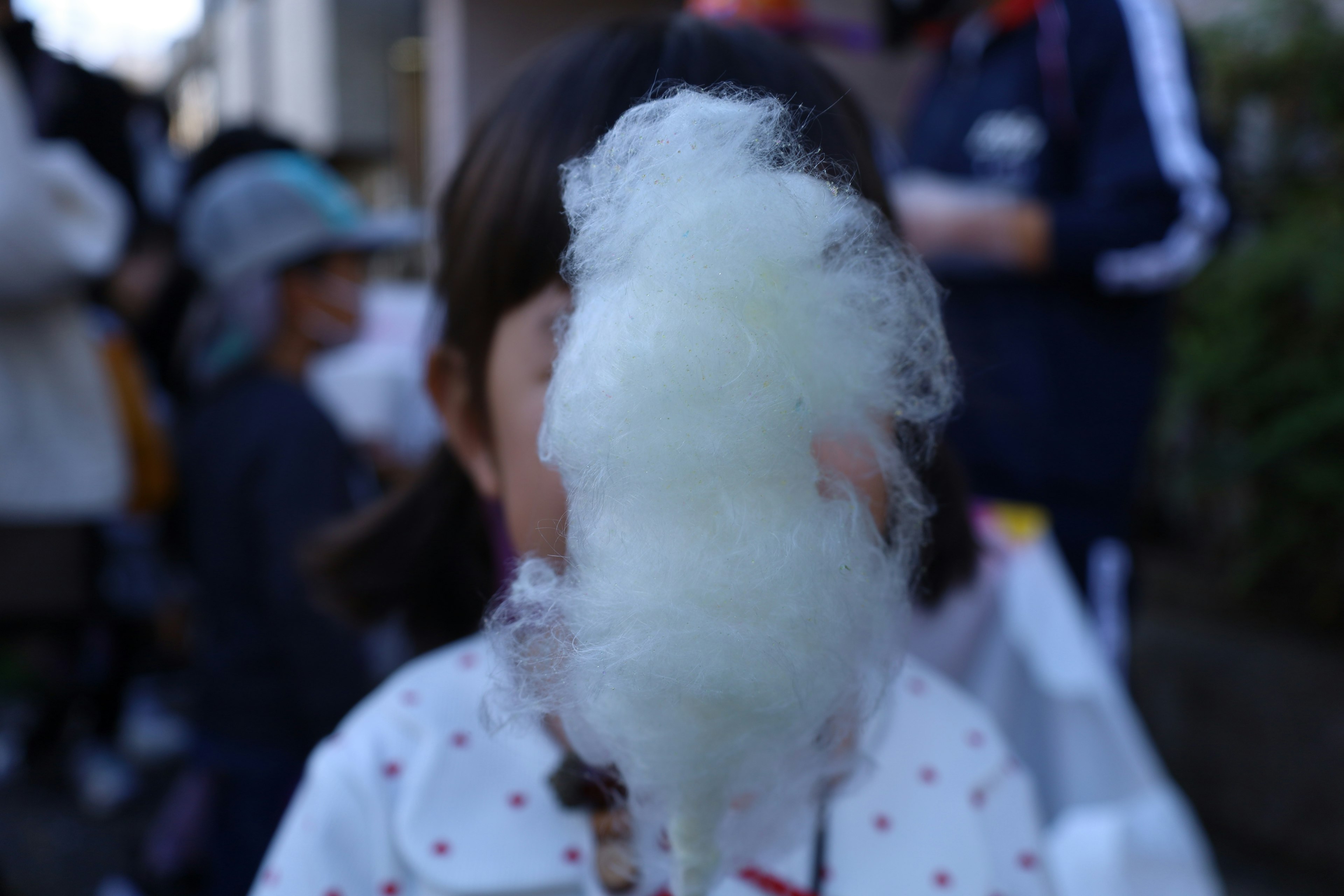 Child holding cotton candy with a blurred background of people