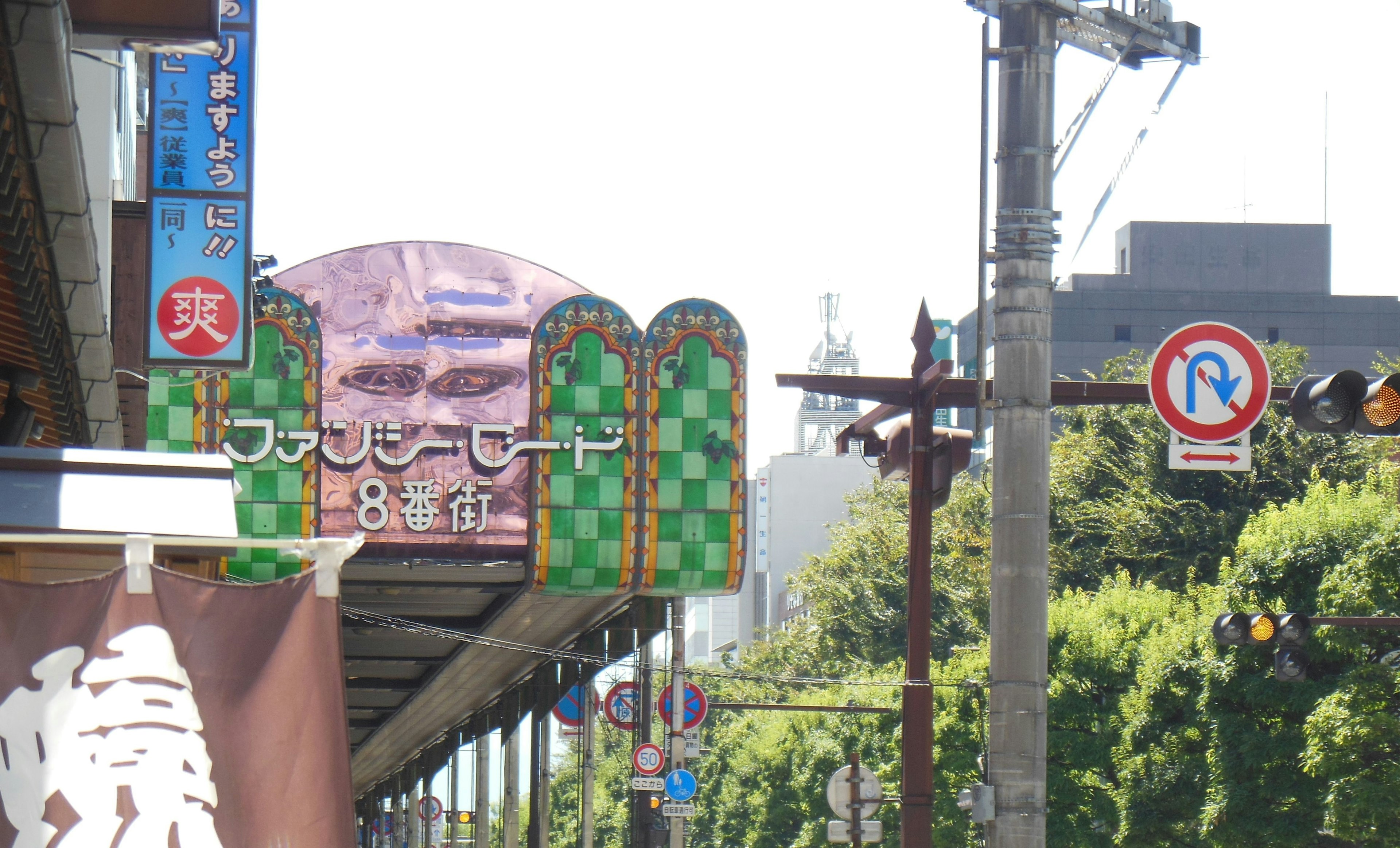 Street view featuring a commercial sign with green tiles and a purple roof