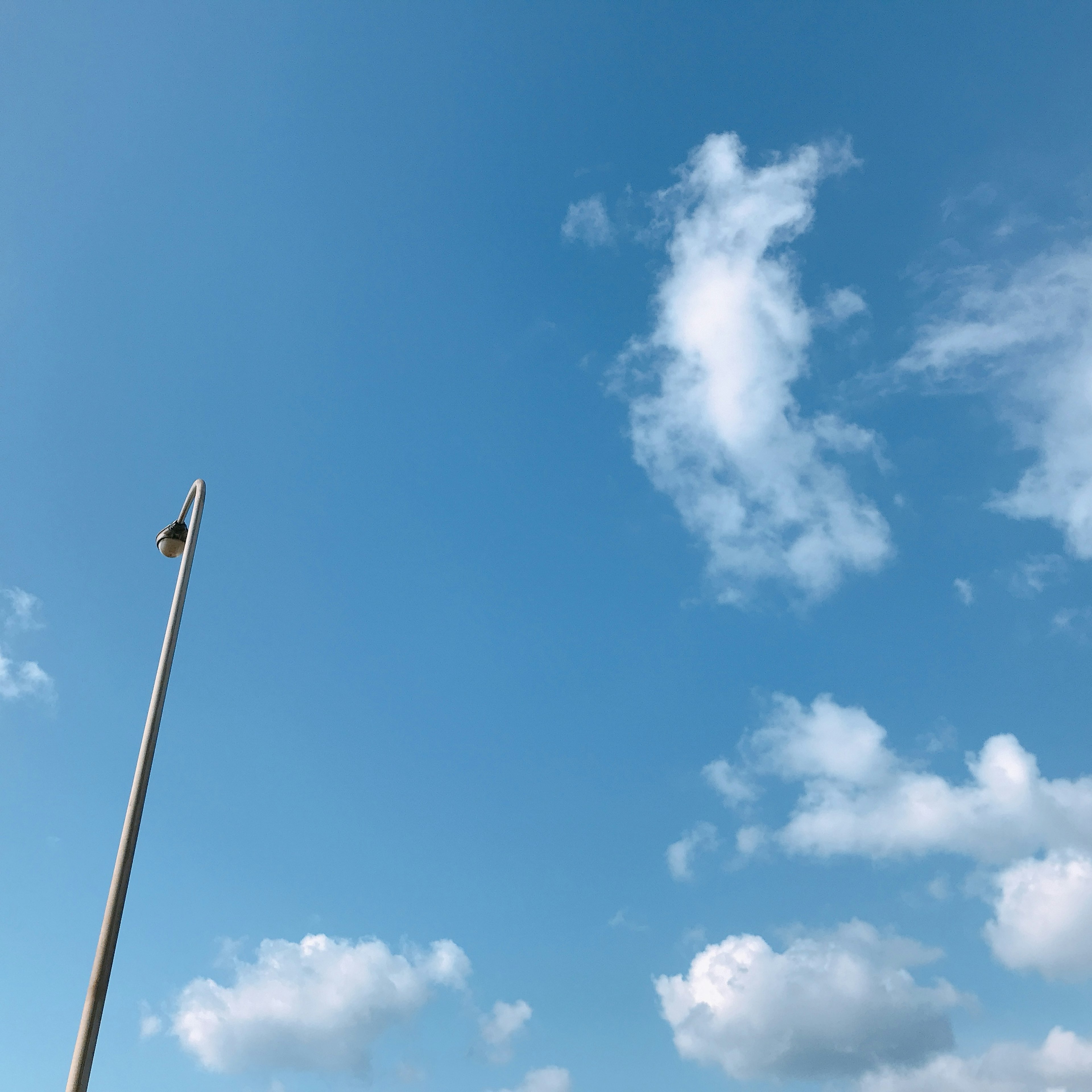 Langit biru dengan awan putih dan tiang lampu