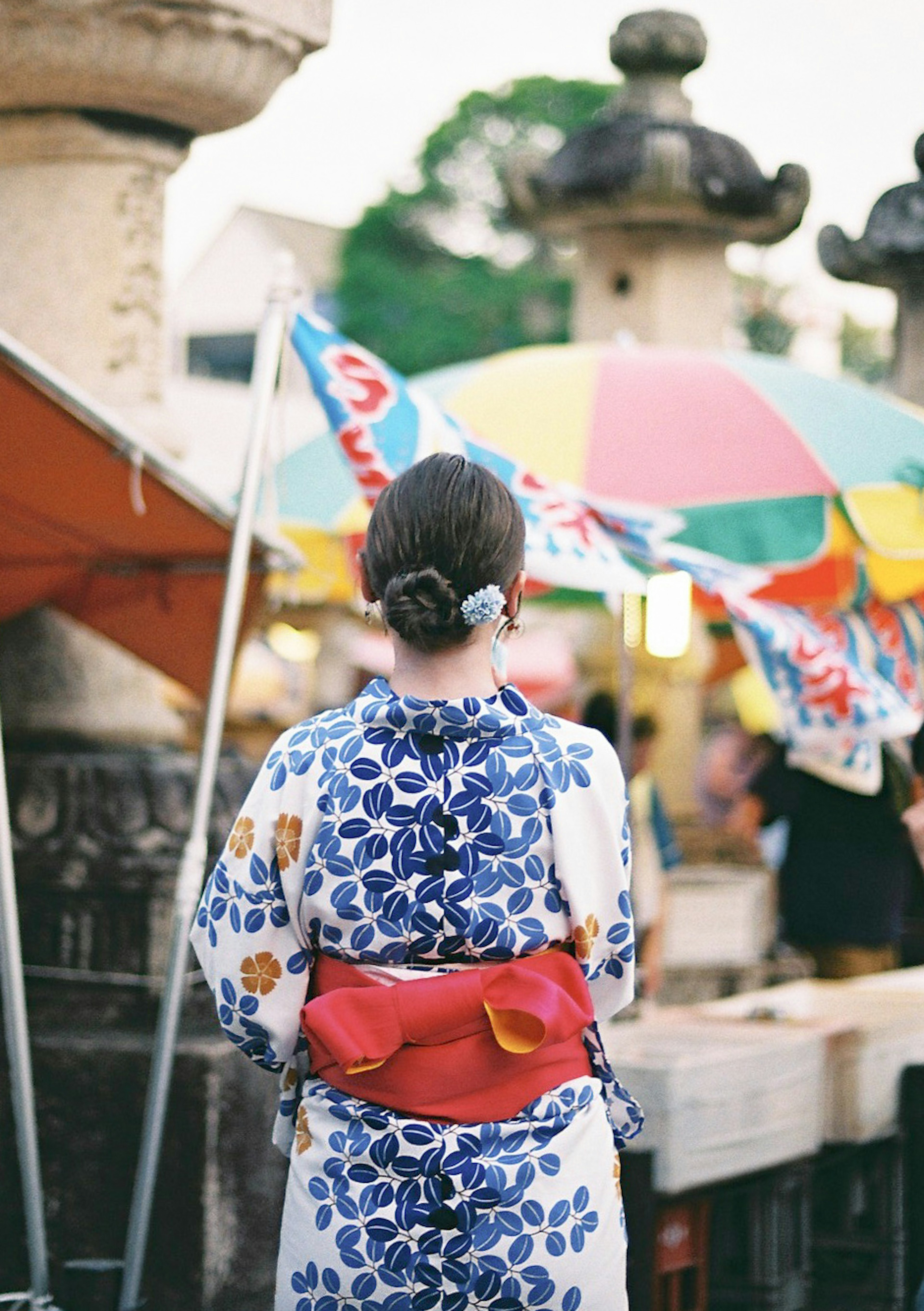 一位穿著和服的女性背對鏡頭站在五彩伞下