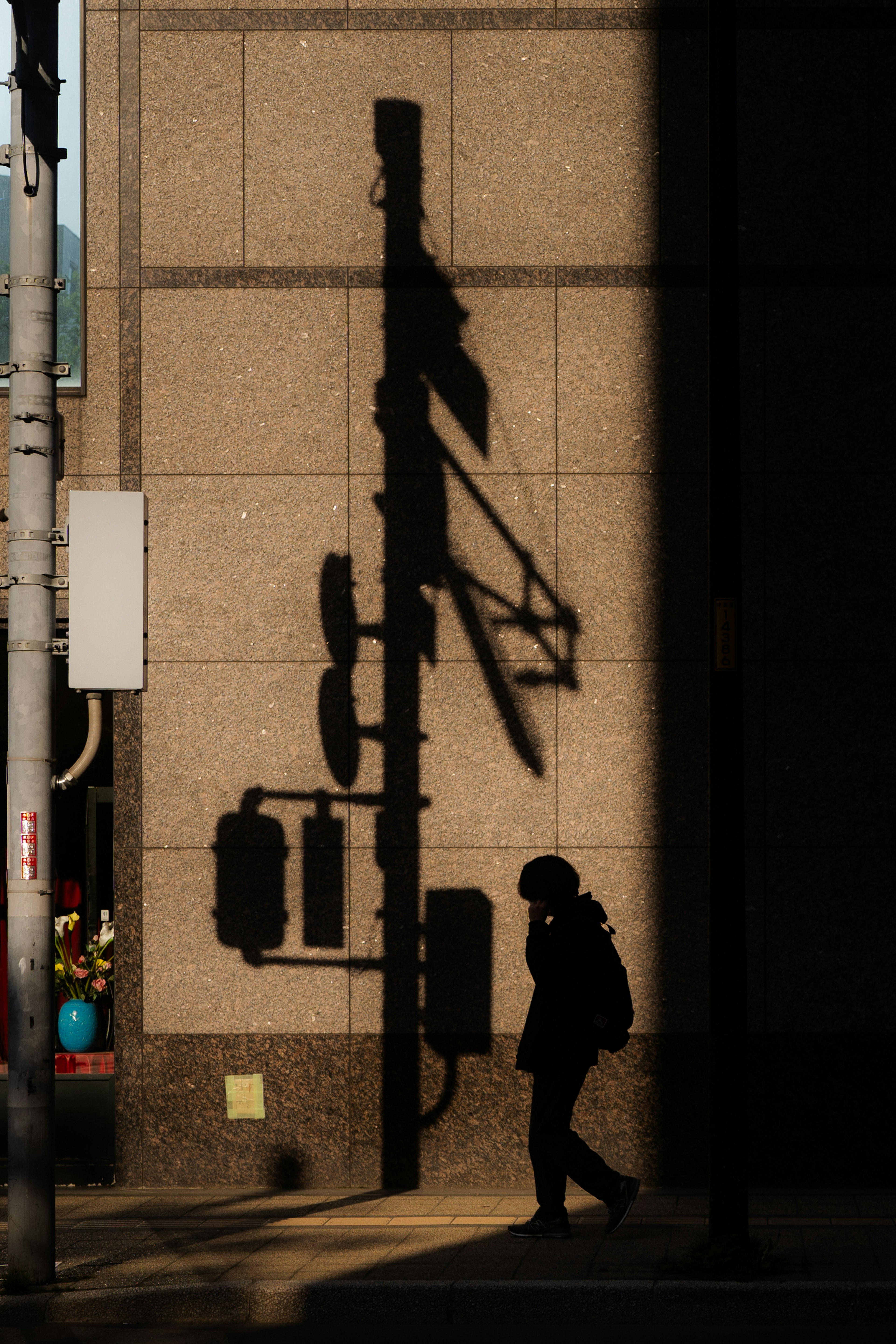 A person walking along a street corner with shadows cast by traffic lights