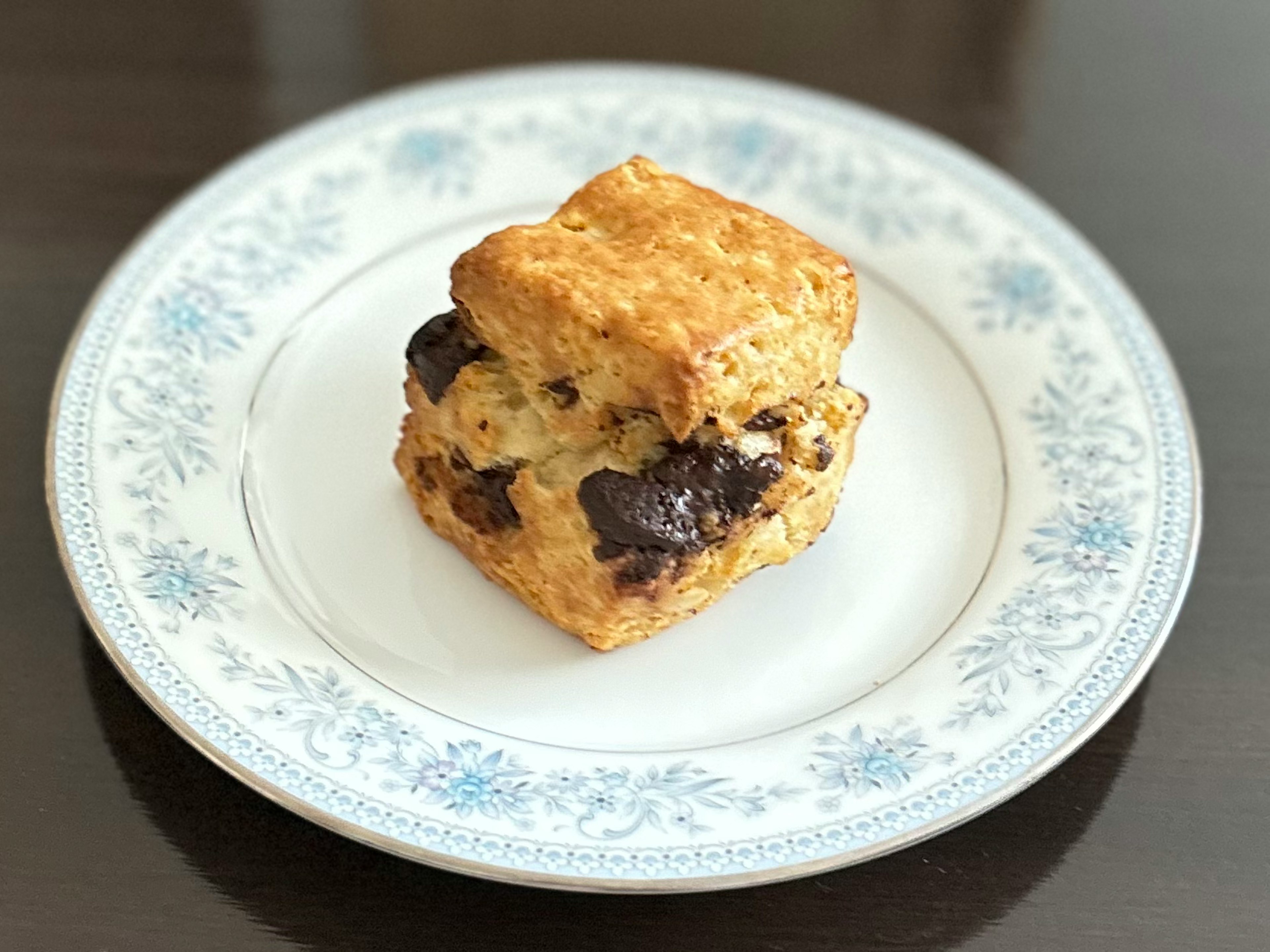 焼き菓子の上にチョコレートチップが挟まれたスコーンが青い花模様の皿に置かれている