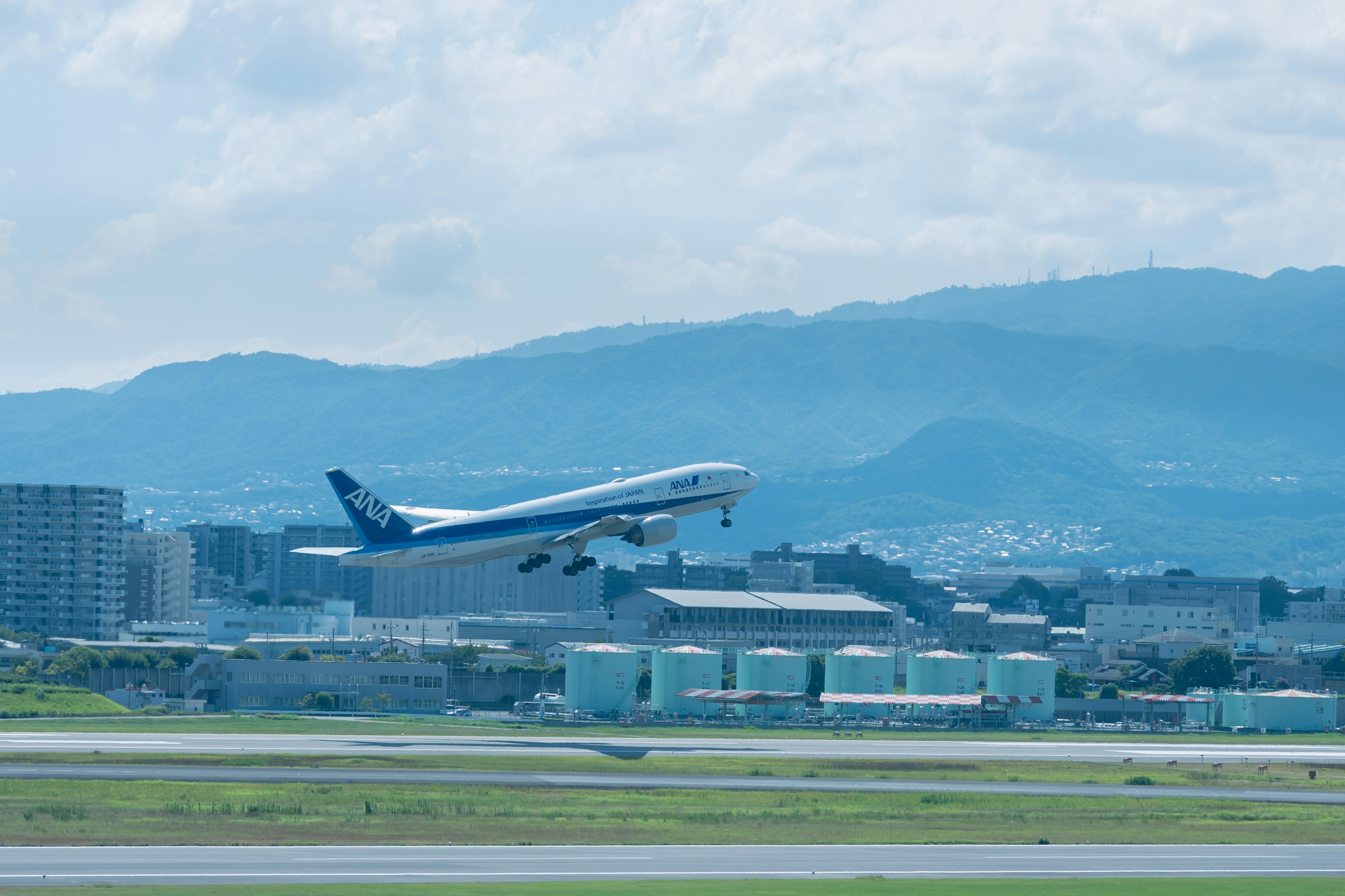 青い空の下で離陸する飛行機と山々が背景