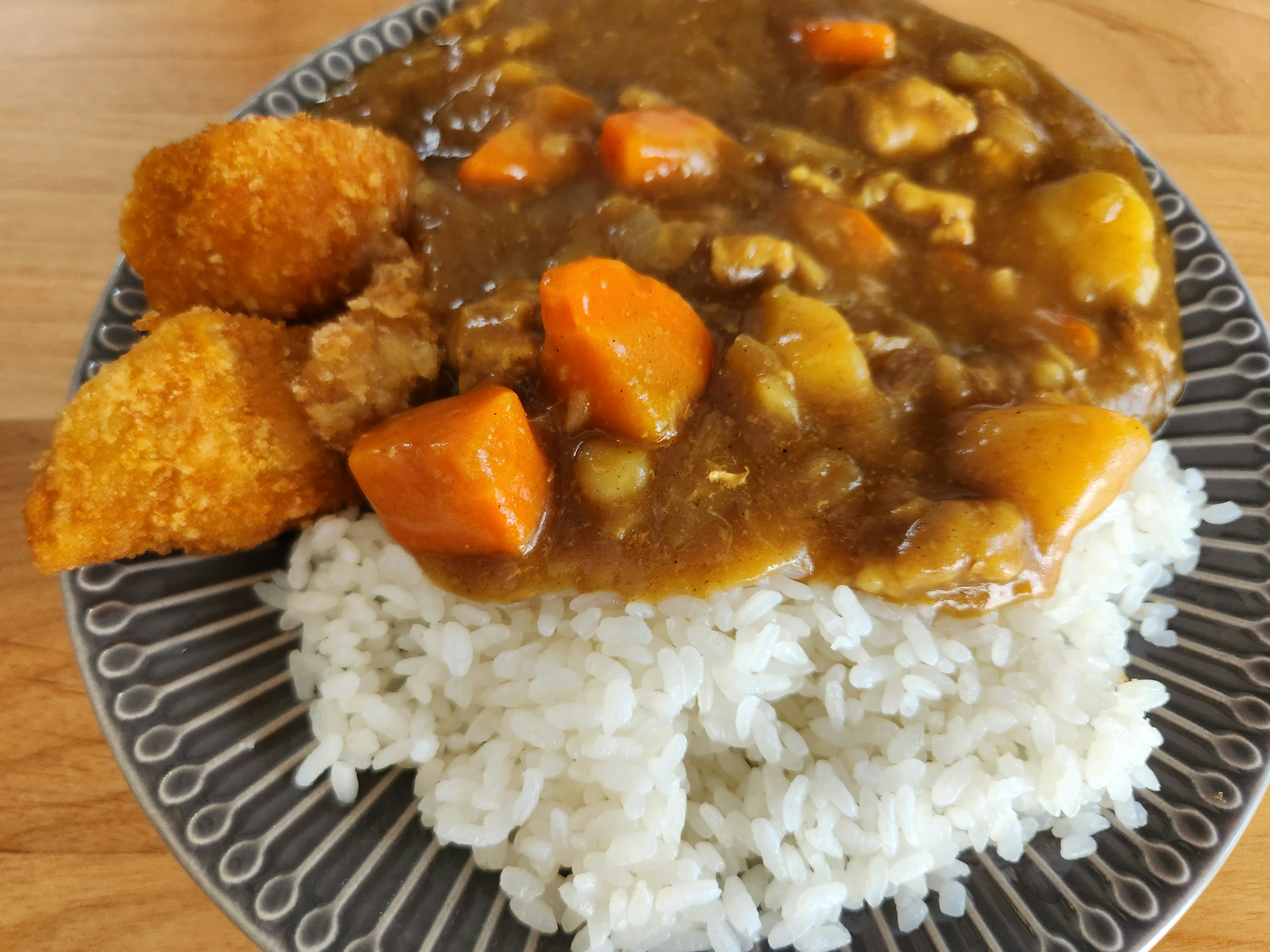 Assiette de riz surmontée de curry et de légumes avec des plats frits en accompagnement