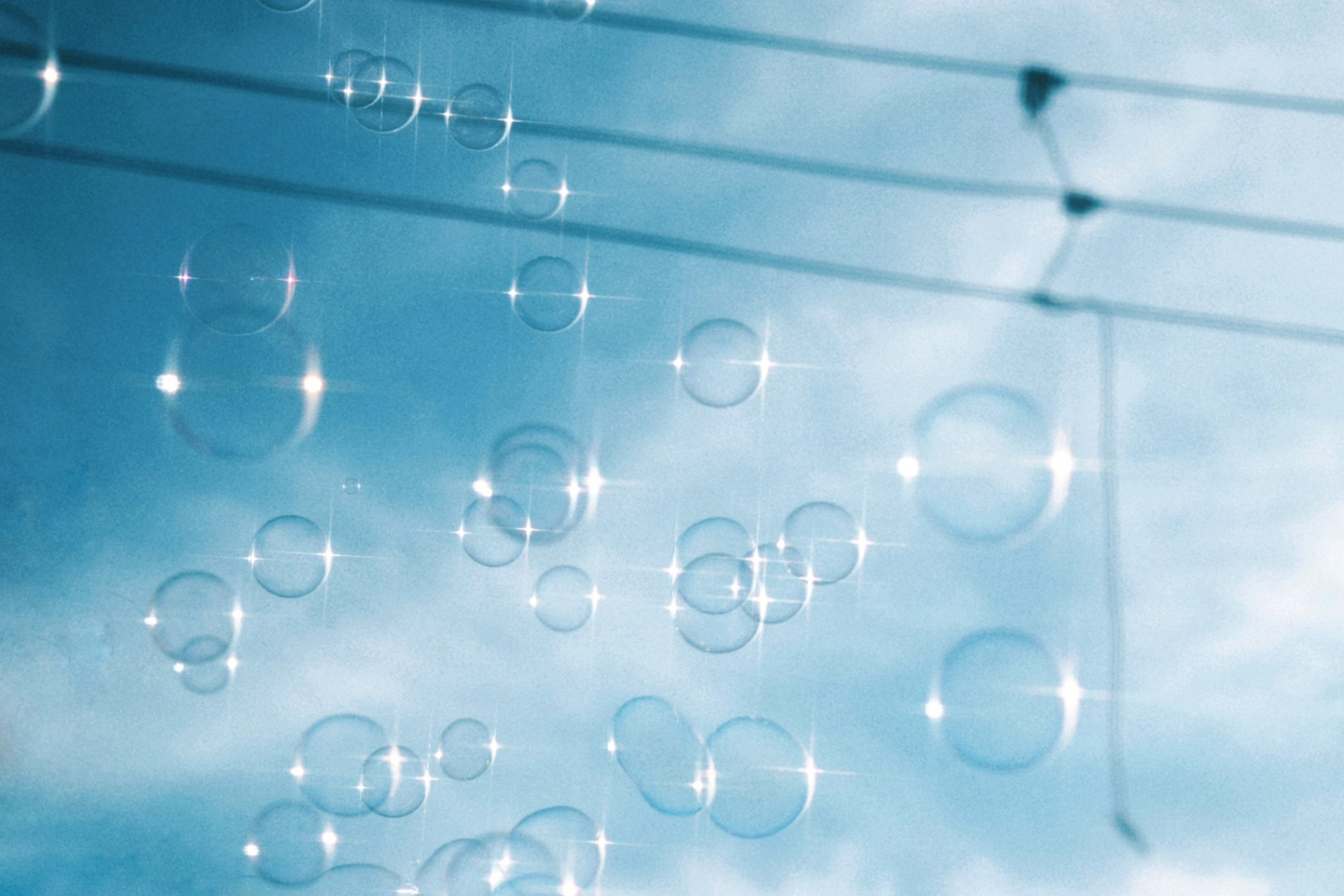 Bubbles floating in a bright blue sky with power lines