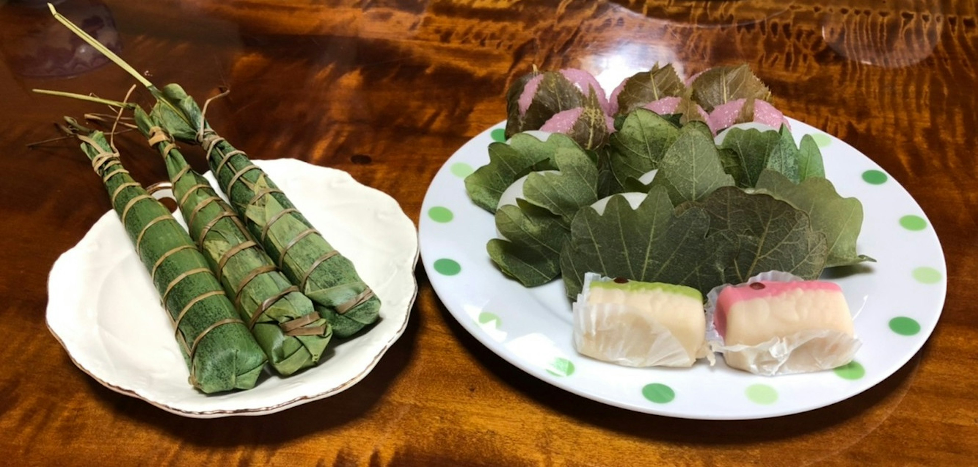 葉で包まれた和菓子と緑のスティックが盛り付けられた皿