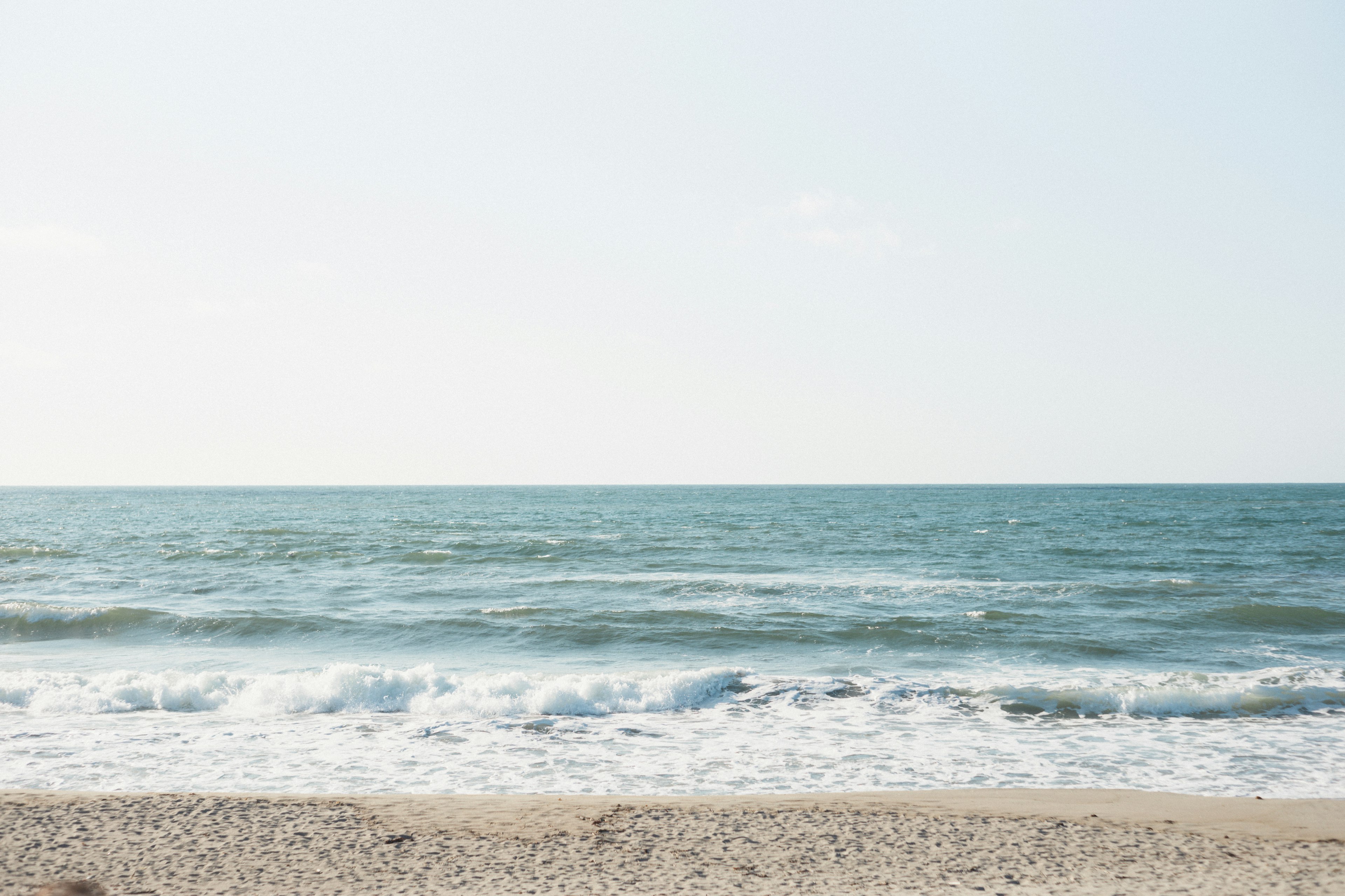 Ruhige Meereslandschaft und blauer Himmel Wellen brechen am Sandstrand