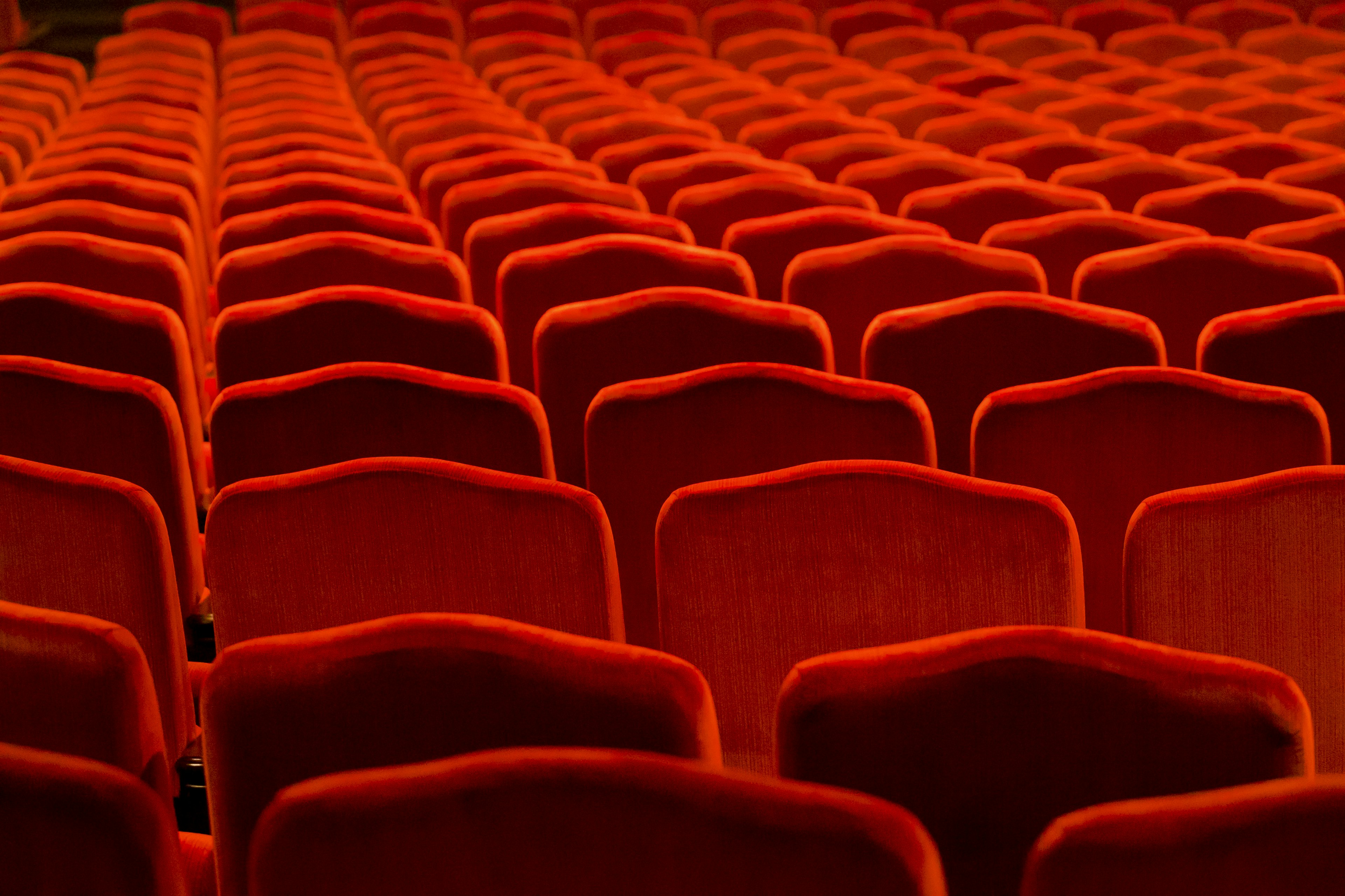 Reihen von roten Theaterstühlen in einem schwach beleuchteten Raum