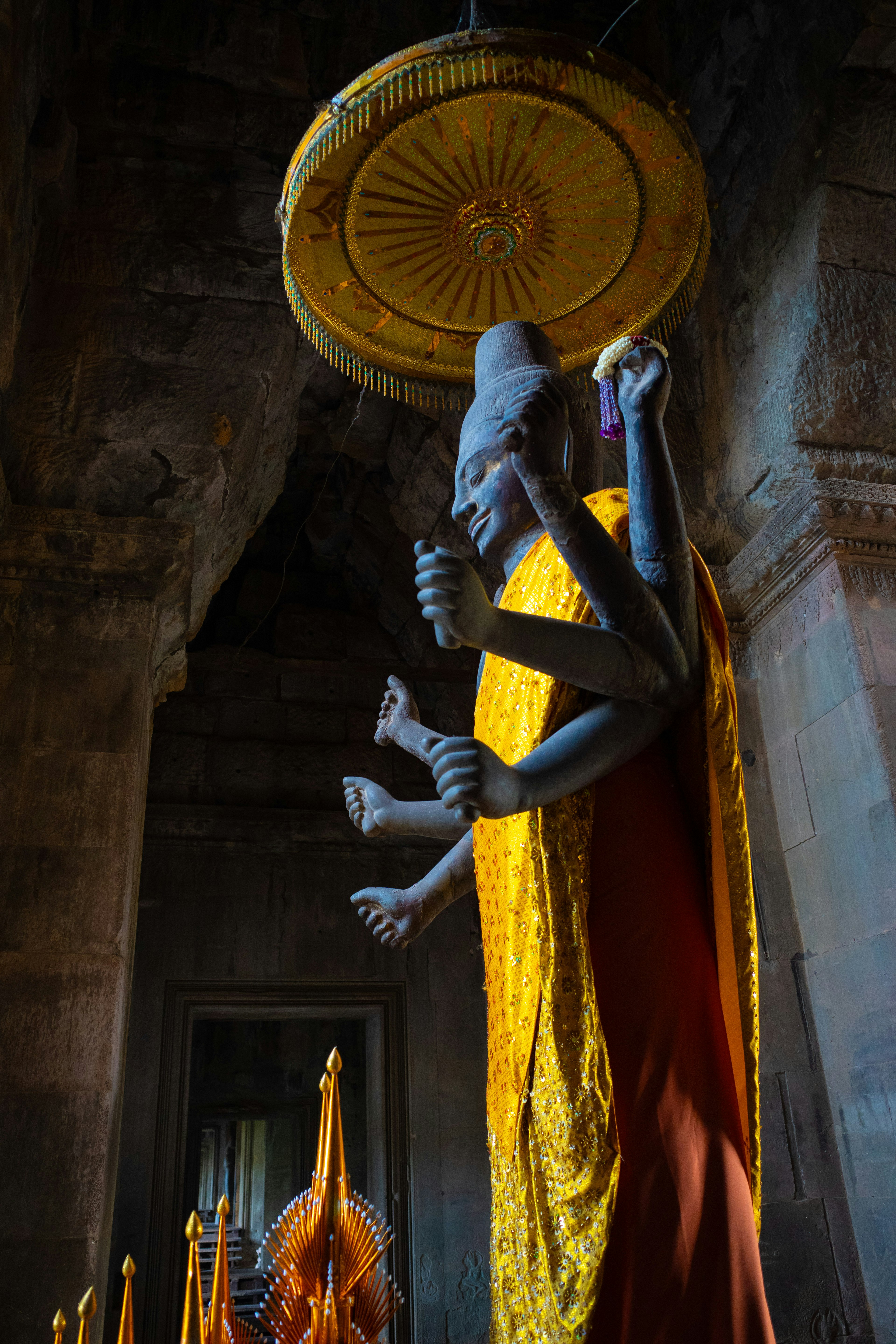 Eine majestätische blaue Statue einer Gottheit mit mehreren Armen unter einem goldenen Baldachin