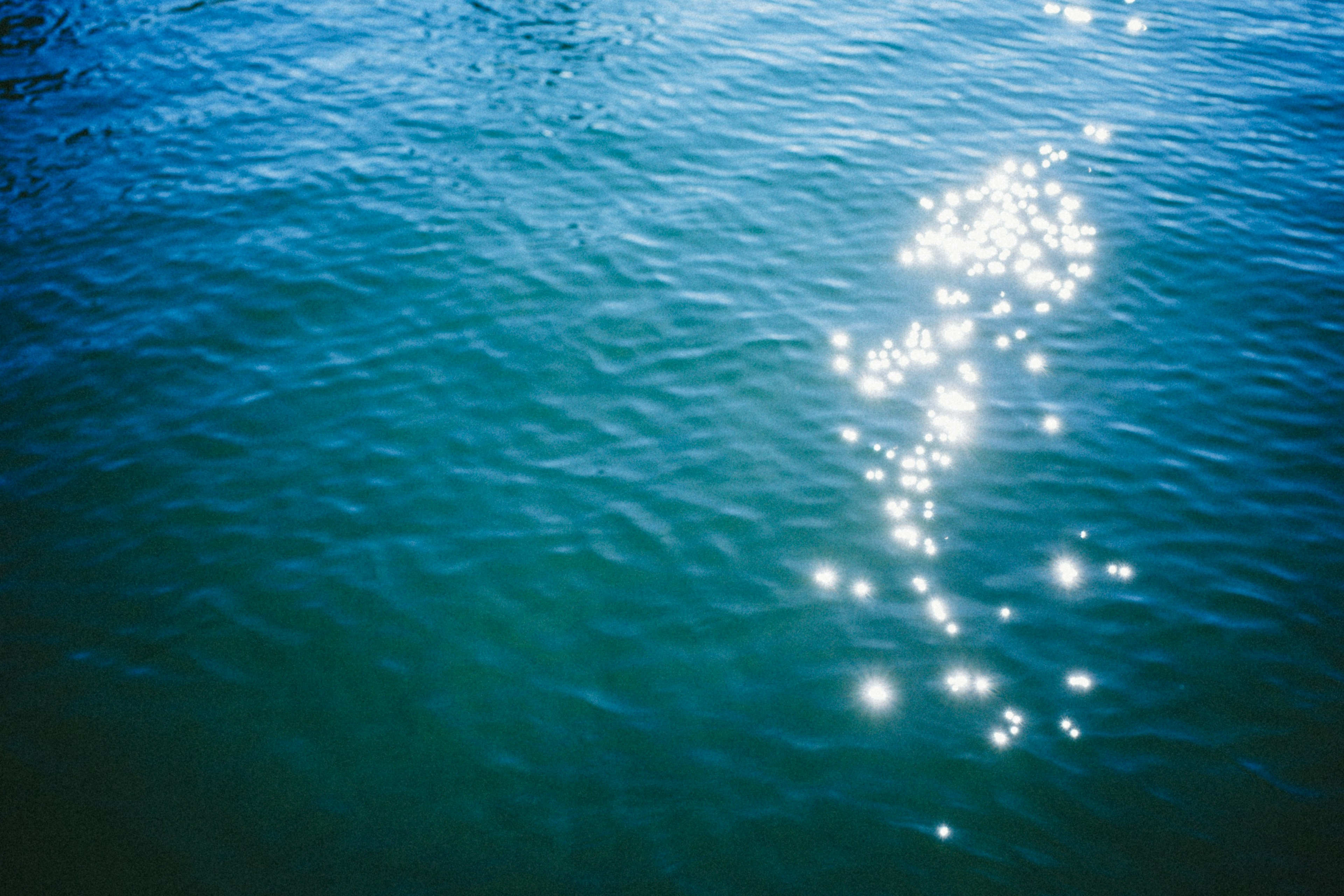 Sparkling sunlight reflections on a blue water surface