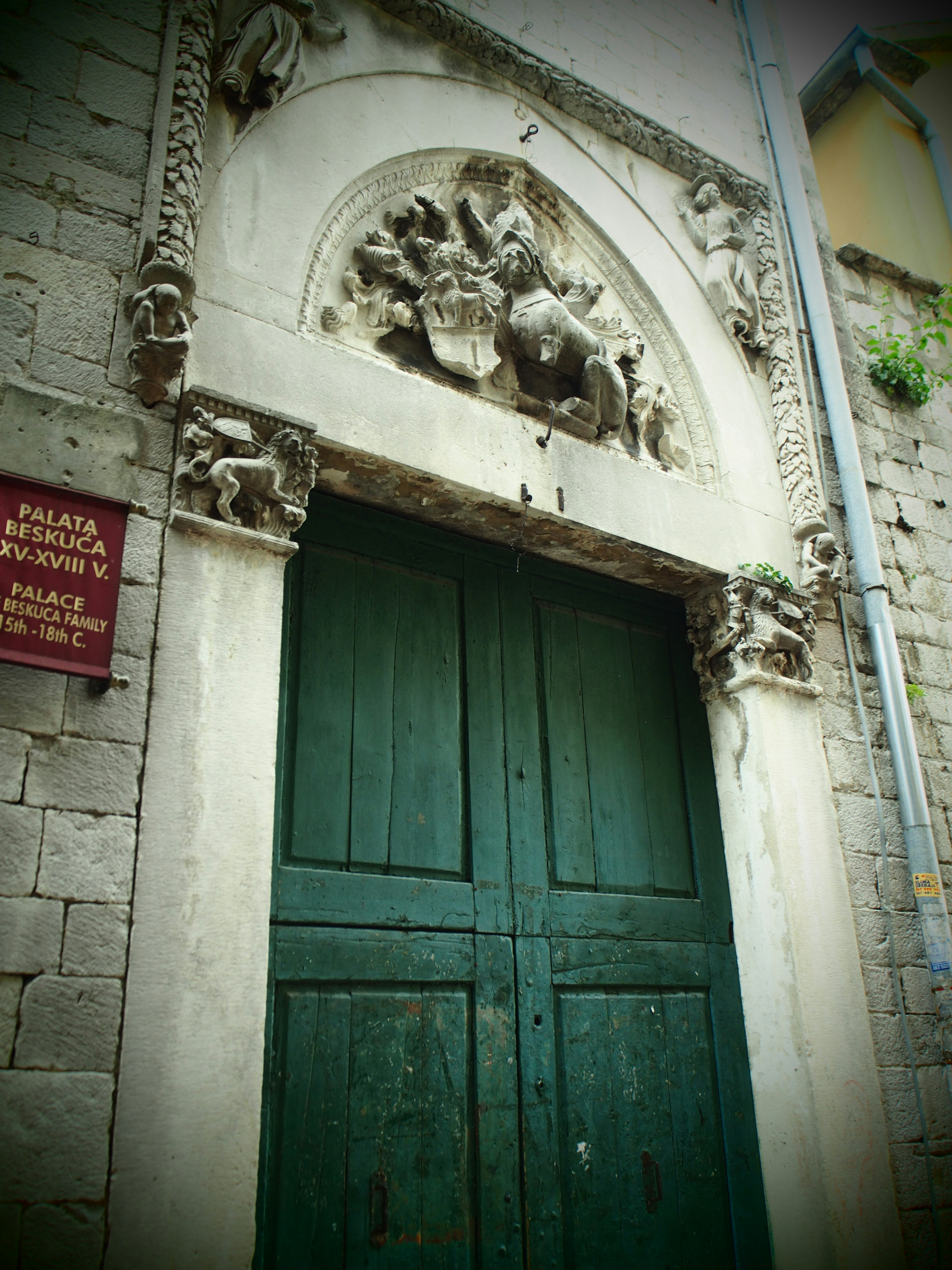 Edificio storico con una porta in legno verde e un arco ornato