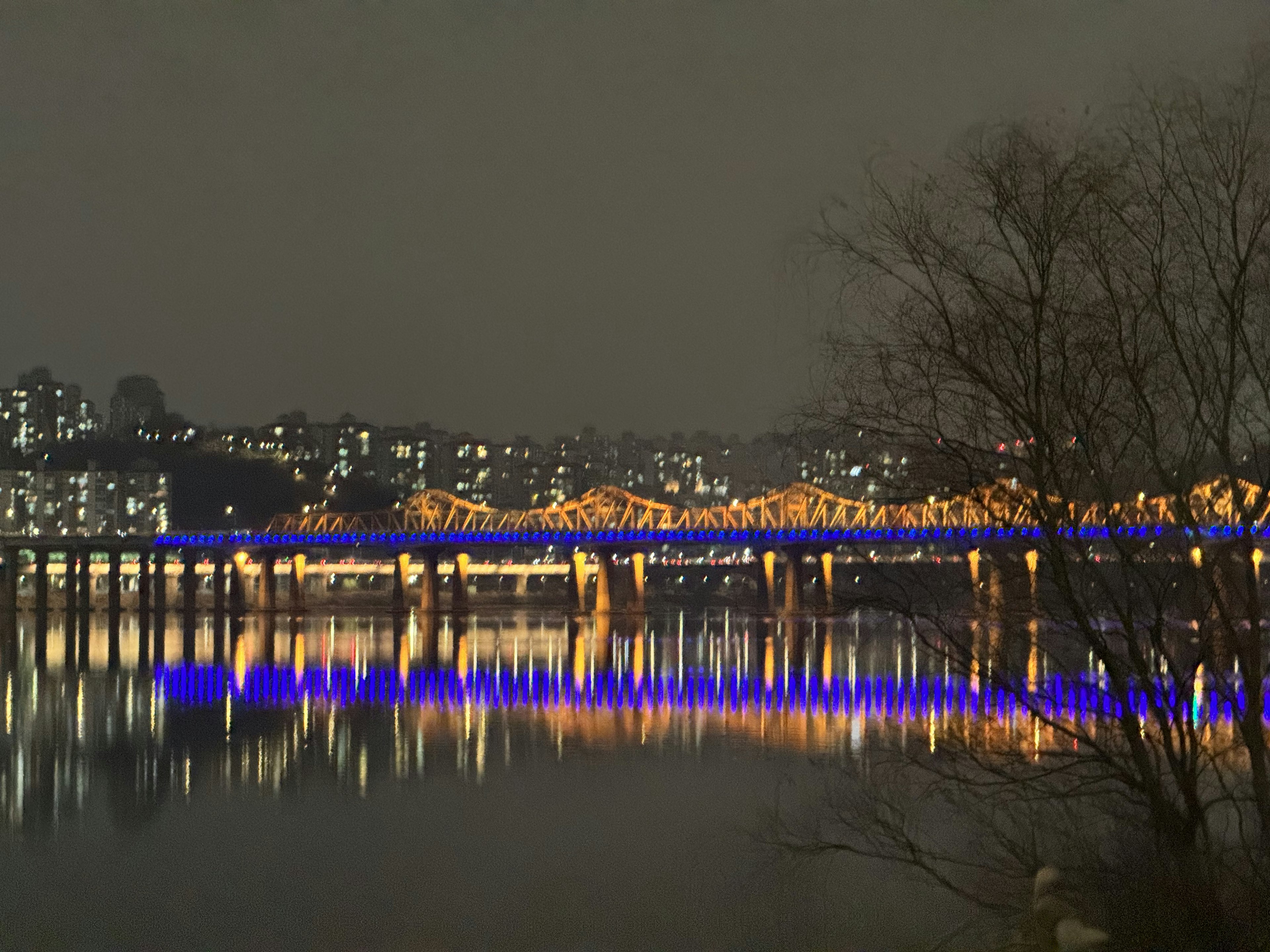 Ponte luminoso e luci della città riflesse nel fiume di notte