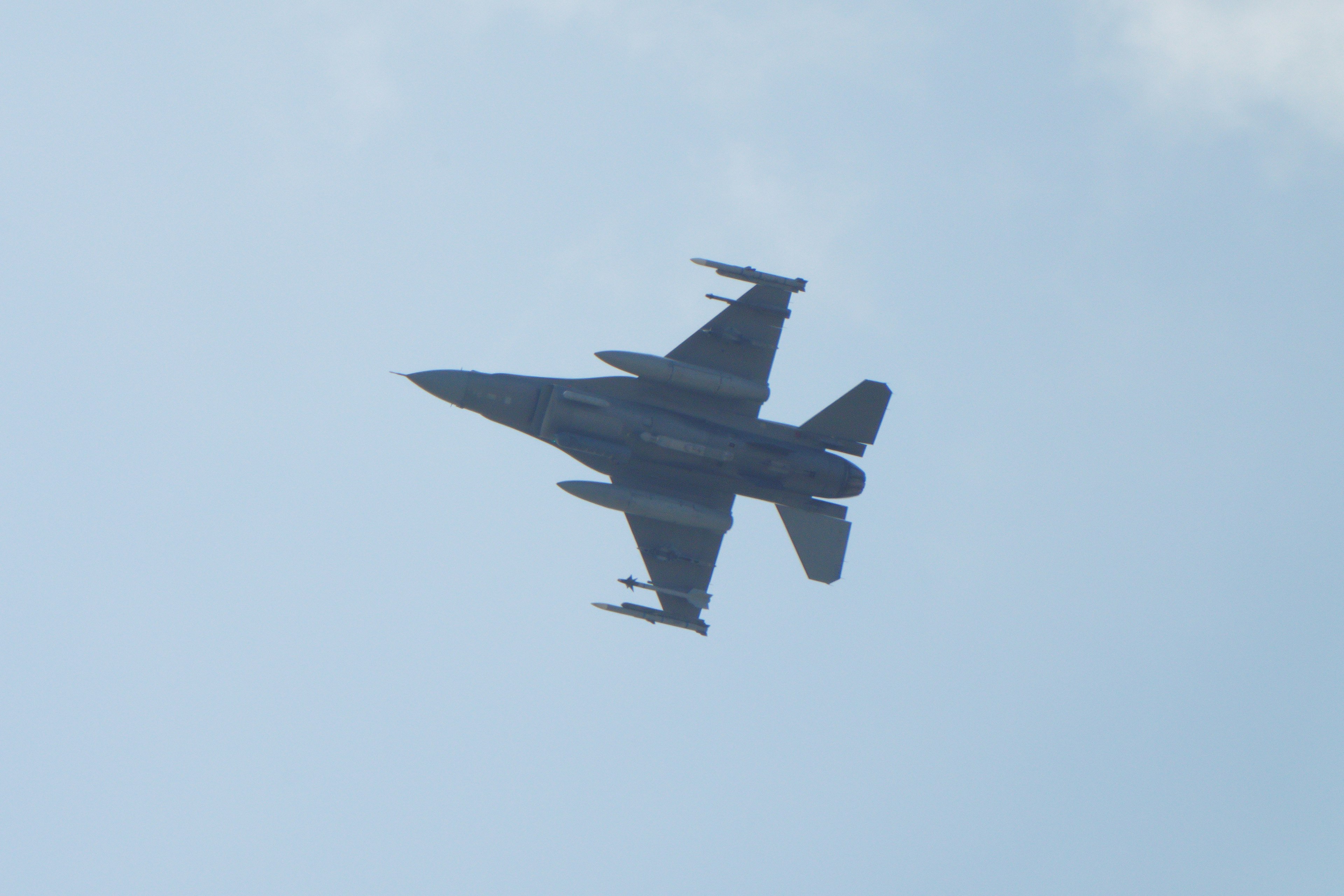 Image d'un avion de chasse volant dans le ciel avec un fond bleu représentant un F-16