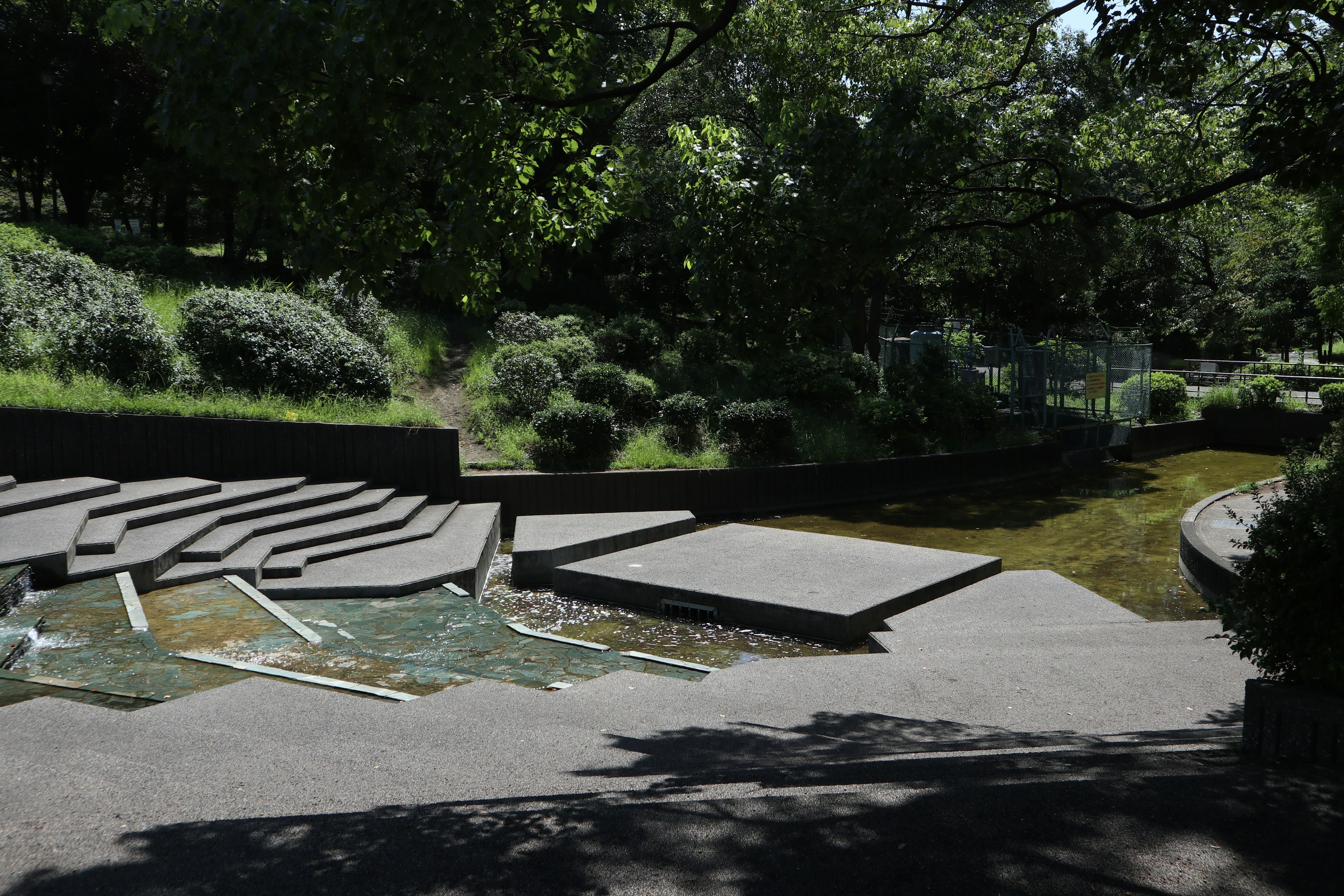 Paisaje de parque exuberante con asientos de concreto en terrazas y vegetación