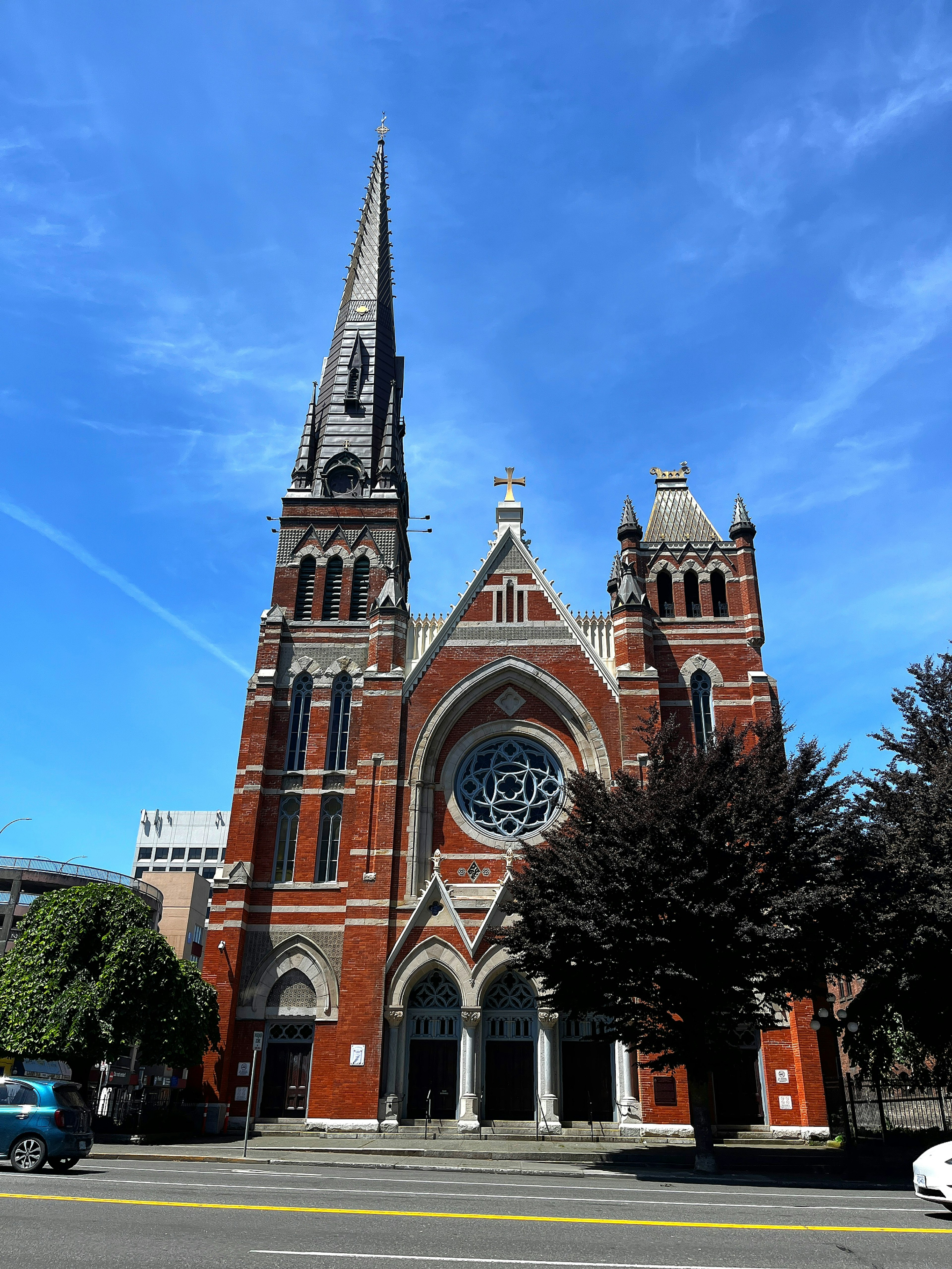 Äußeres einer roten Backsteinkirche mit hohem Turm und schönem Buntglasfenster