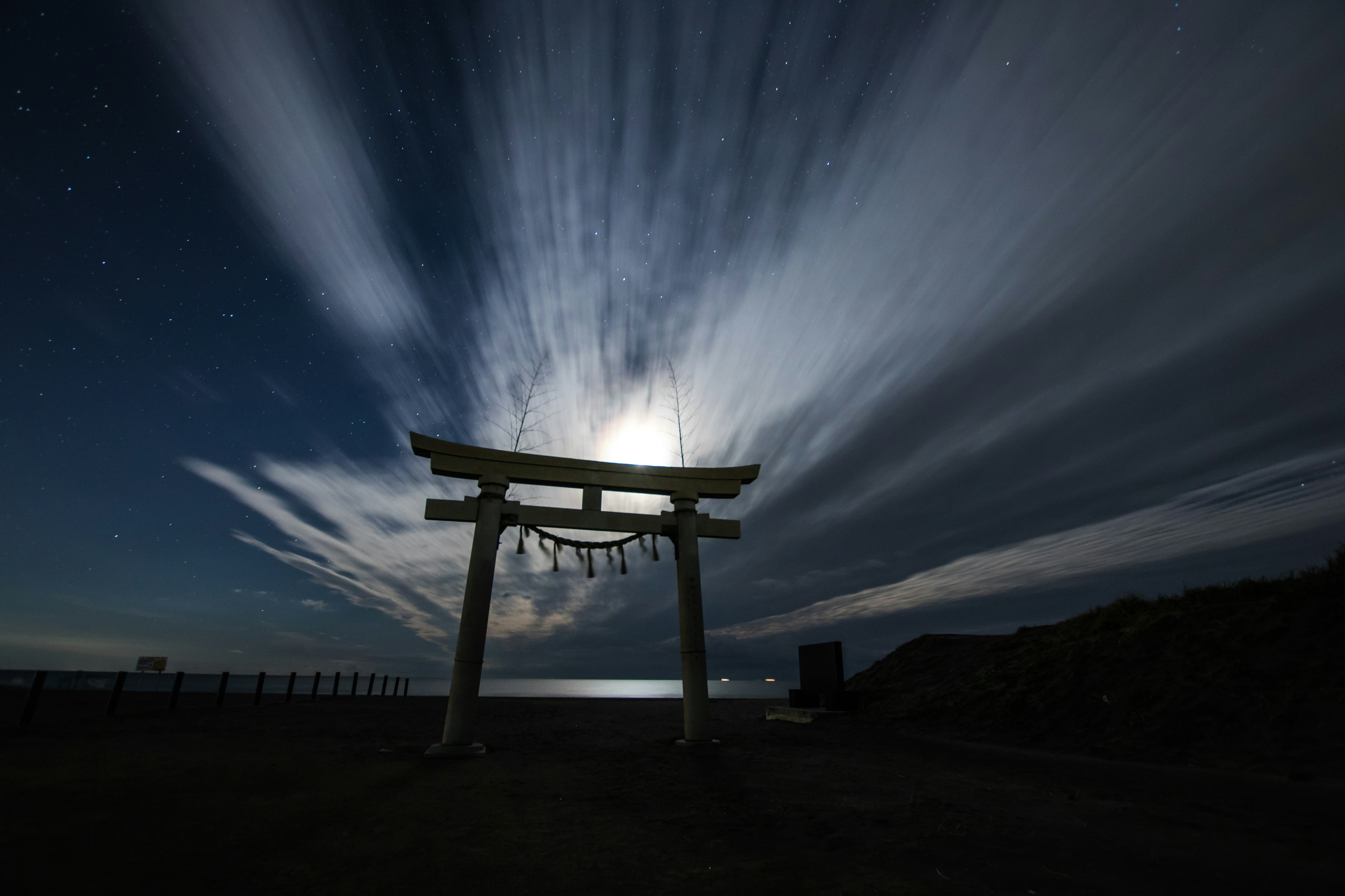 Torii iluminado por la luz de la luna con nubes dramáticas en el cielo nocturno