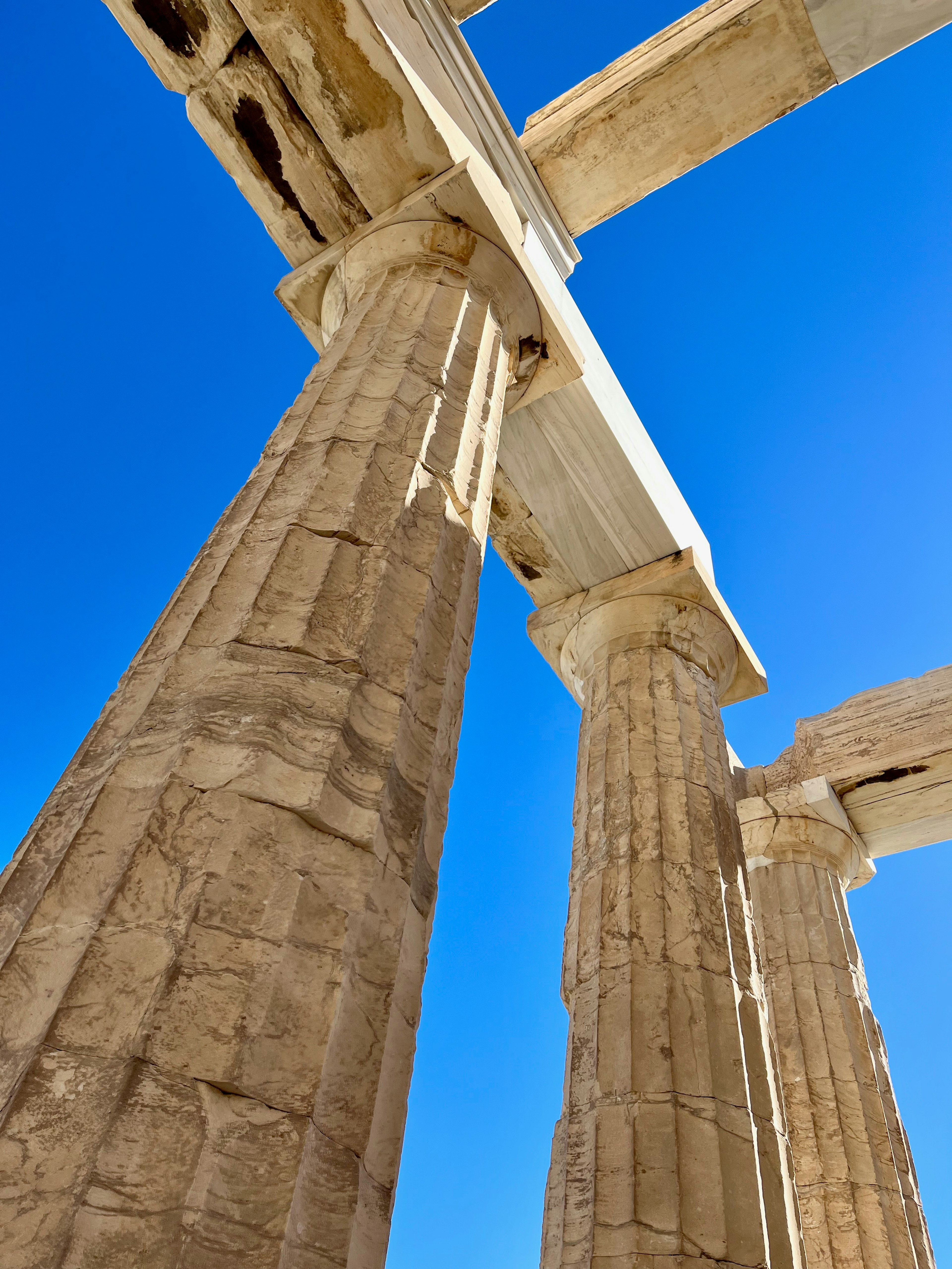 Ancient Greek columns and arch under a clear blue sky