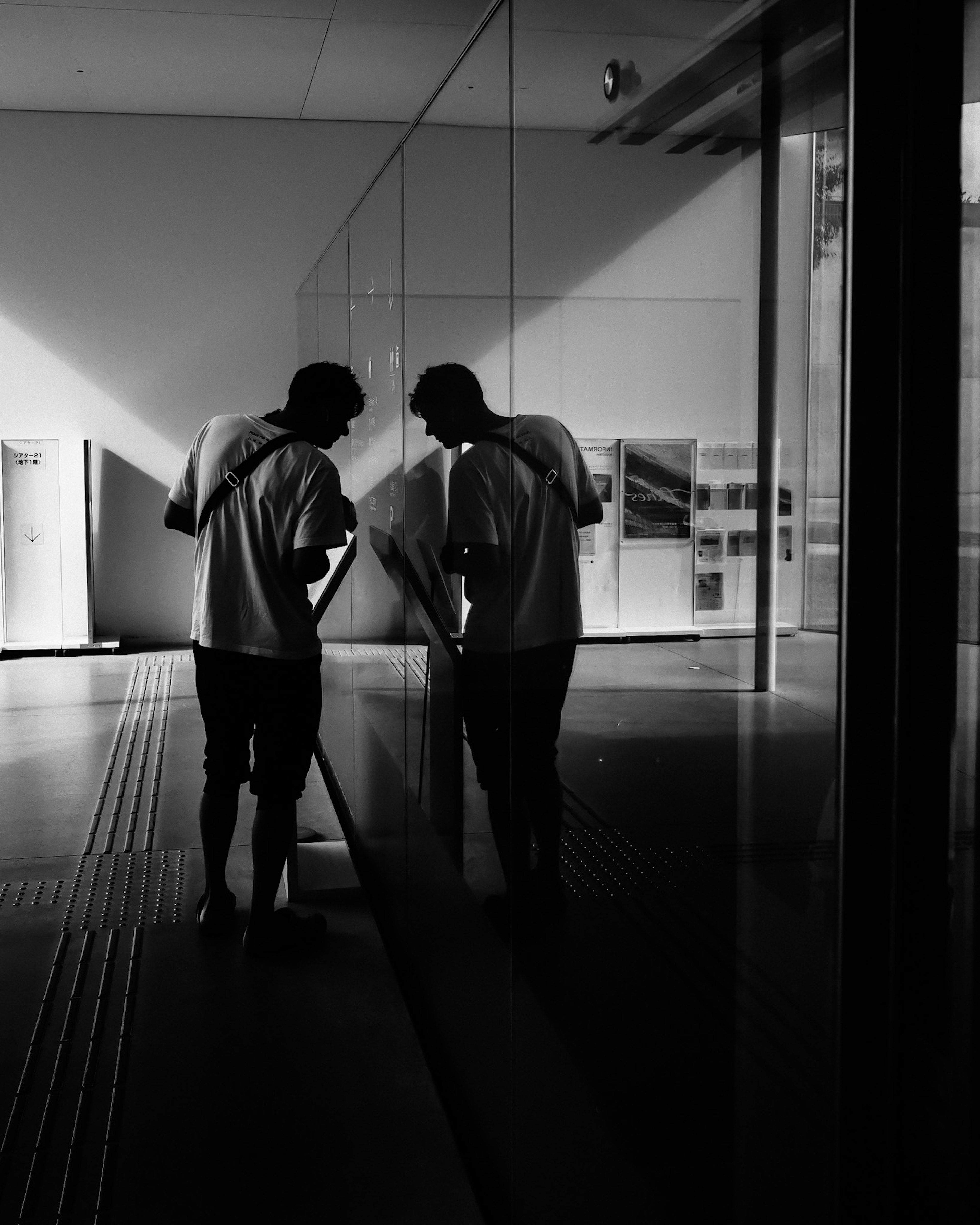 Two men observing something in front of a mirror in a black and white image