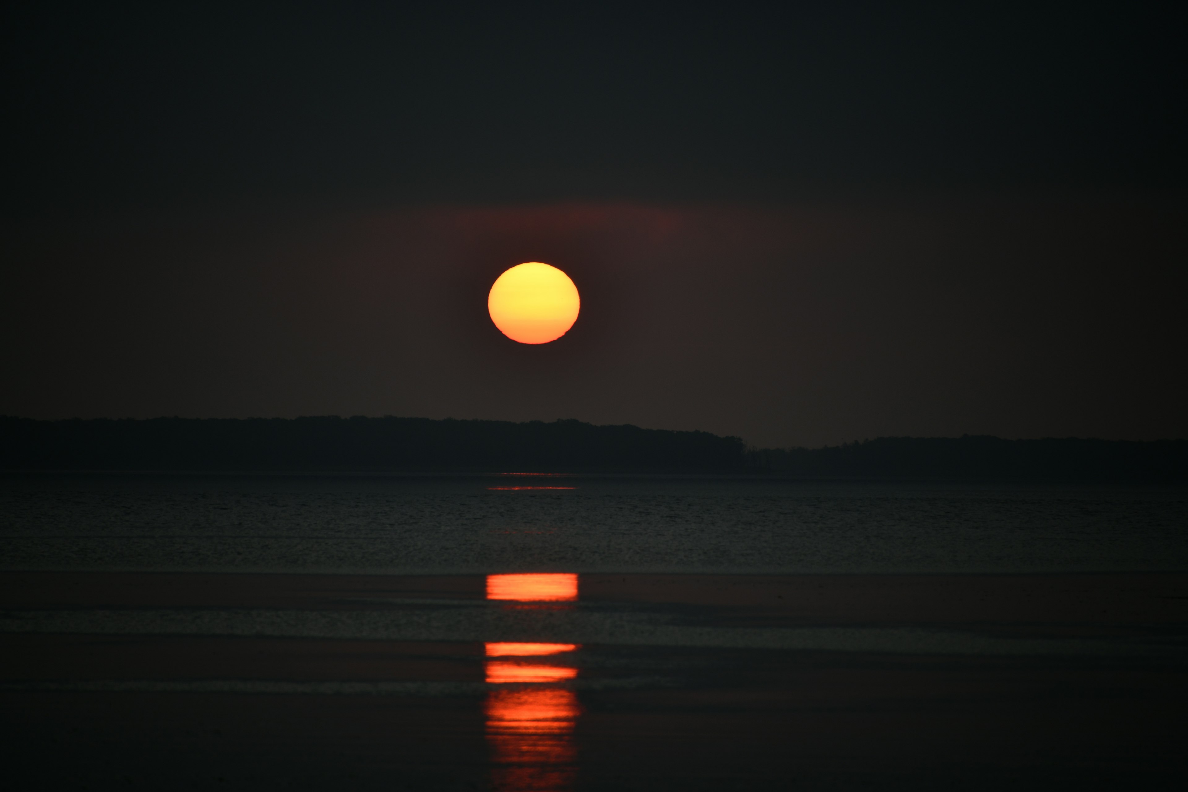 暗い水面に映る夕日とその反射