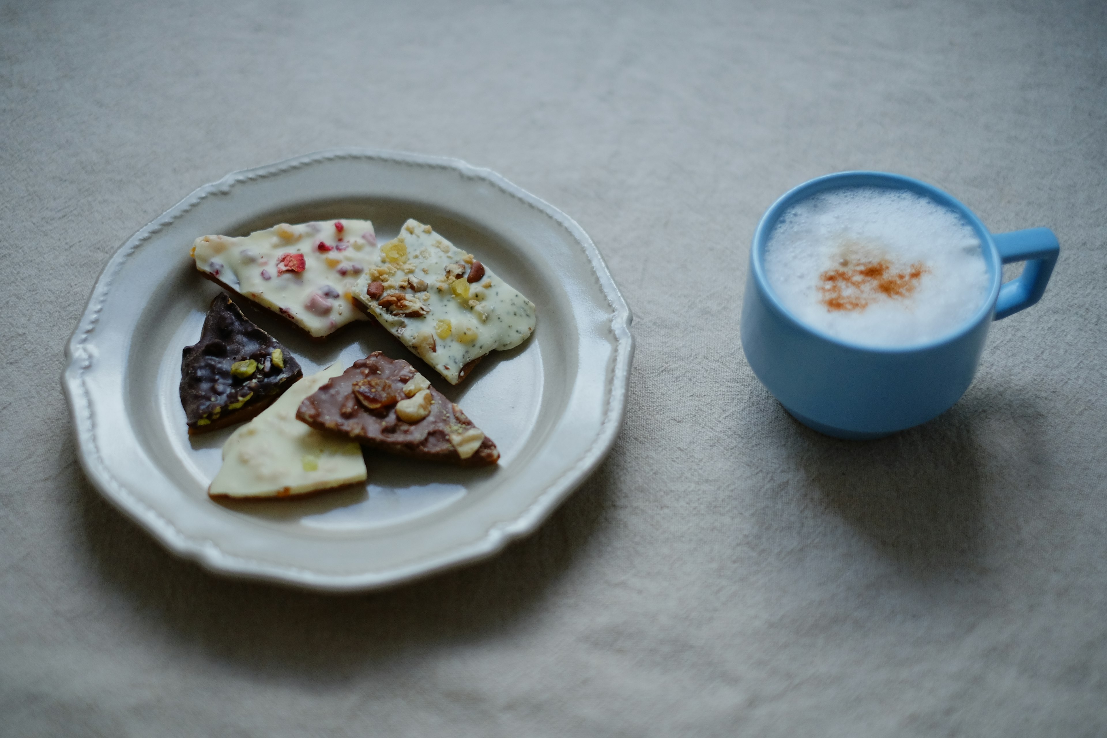 Un piatto con biscotti colorati e una tazza blu di bevanda schiumosa