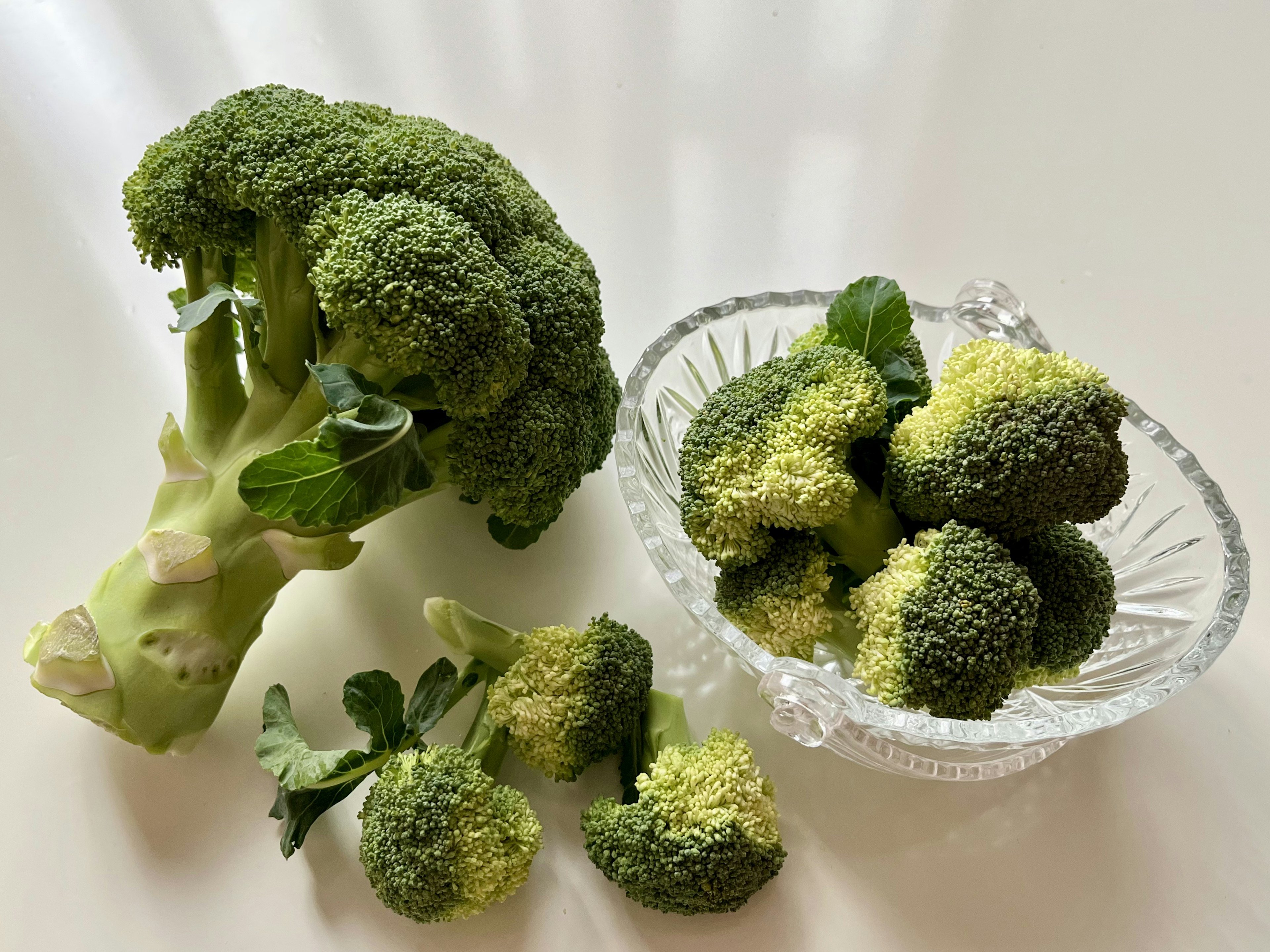 Un bouquet de brocoli frais avec des fleurettes de brocoli plus petites dans un bol en verre