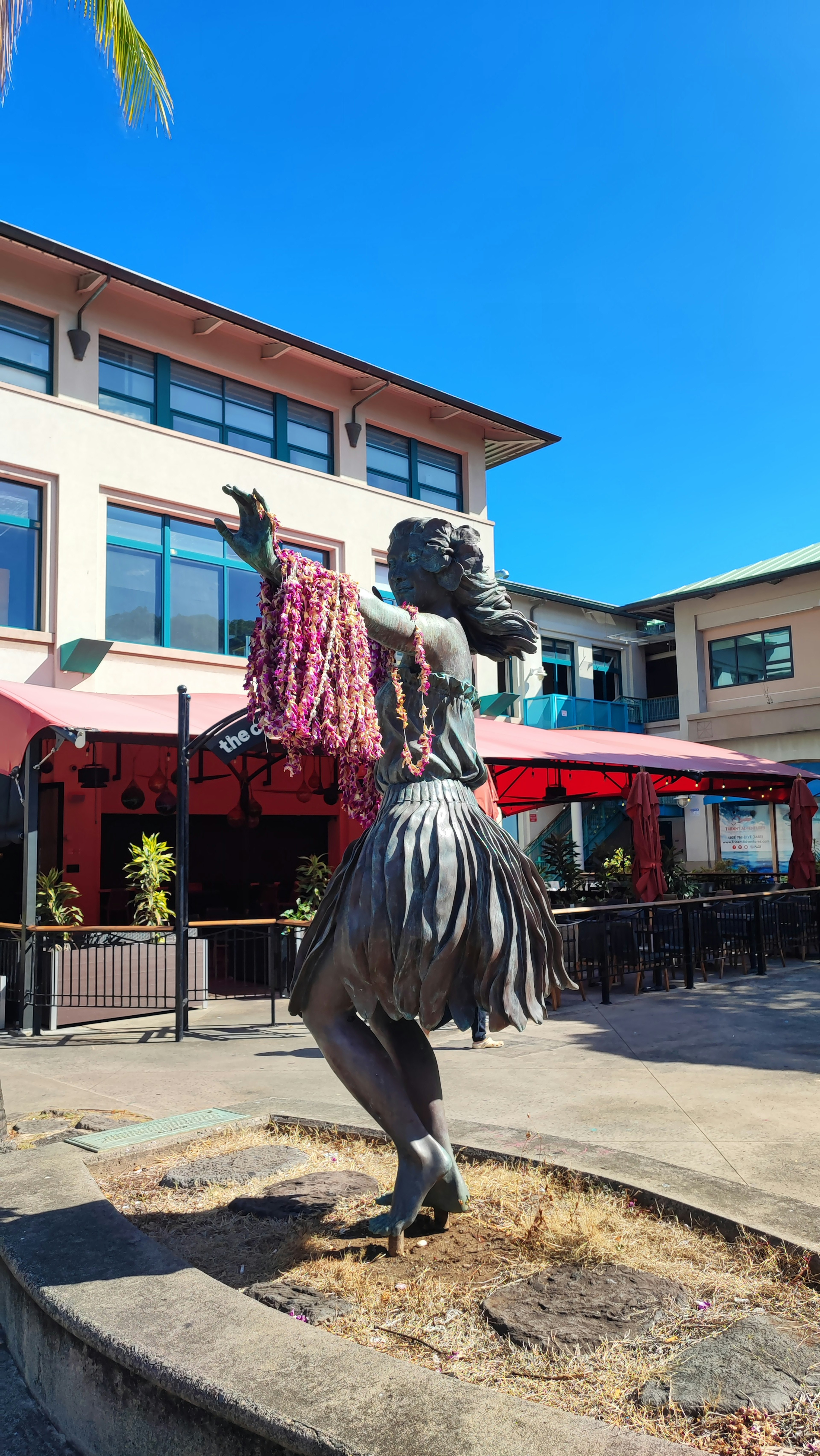 Bronze statue of a dancer in Hawaiian style with a vibrant background