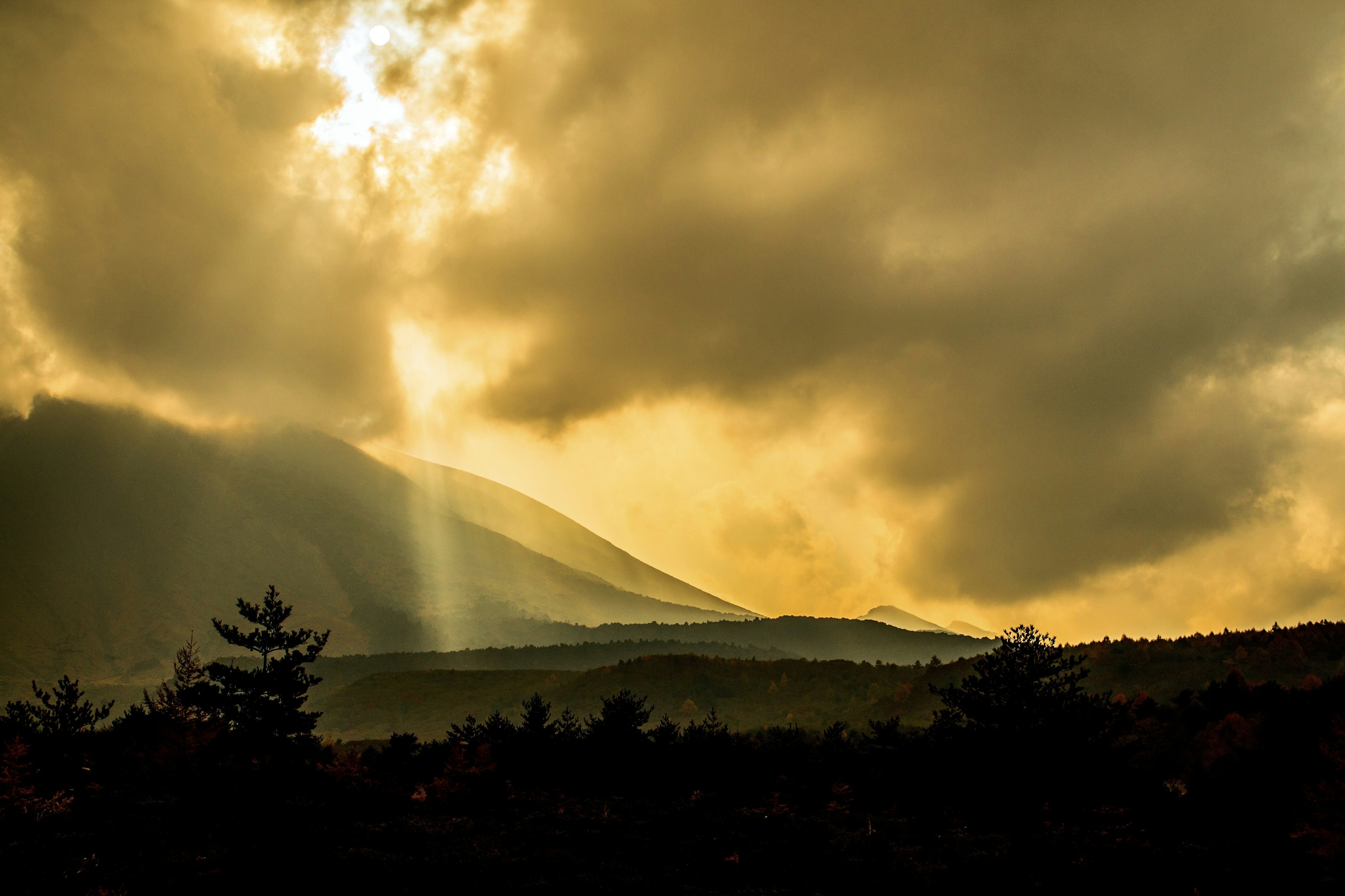 山々と雲に囲まれた金色の光が差し込む風景