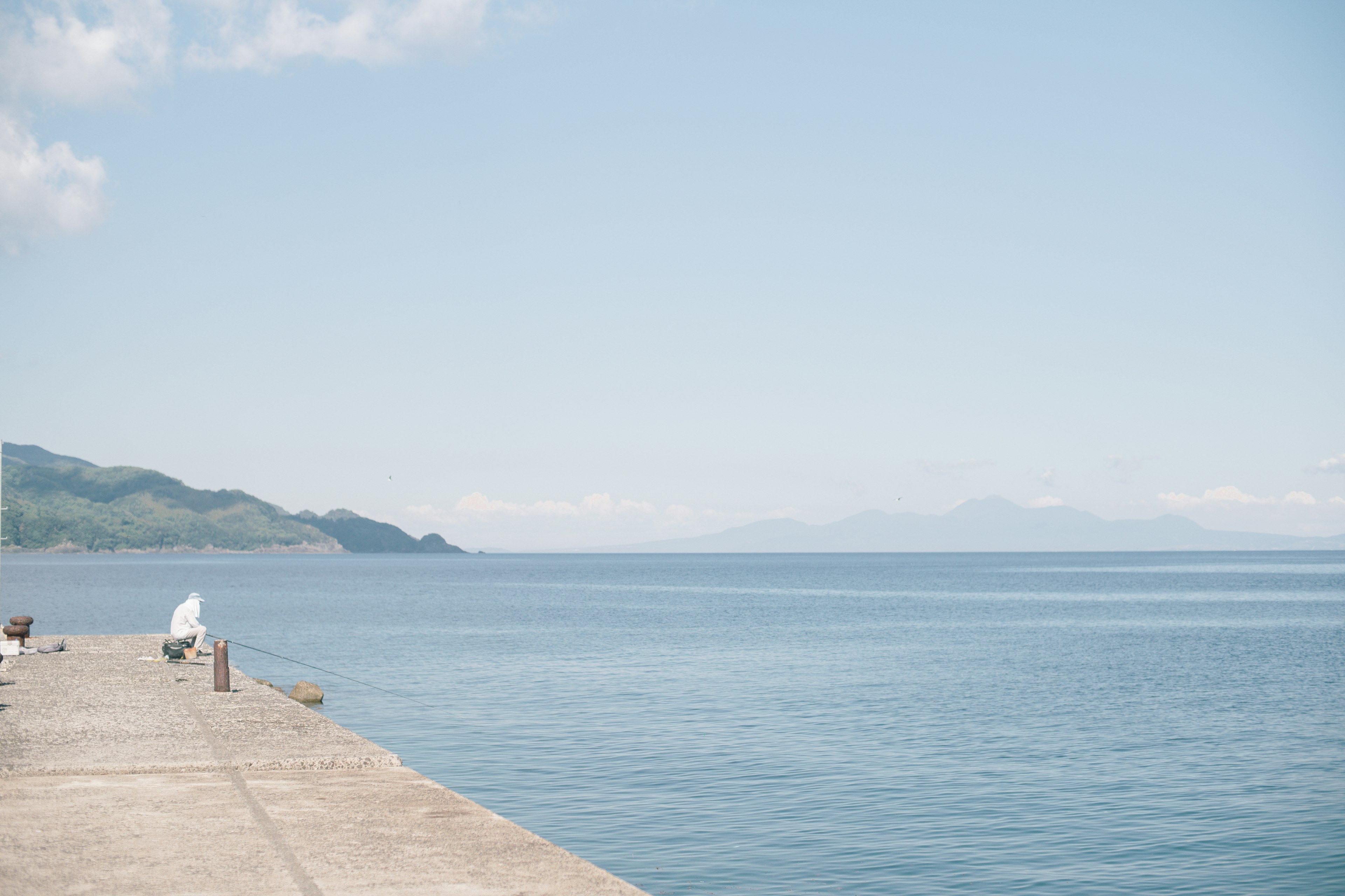 穏やかな海と青空の風景に立つ人