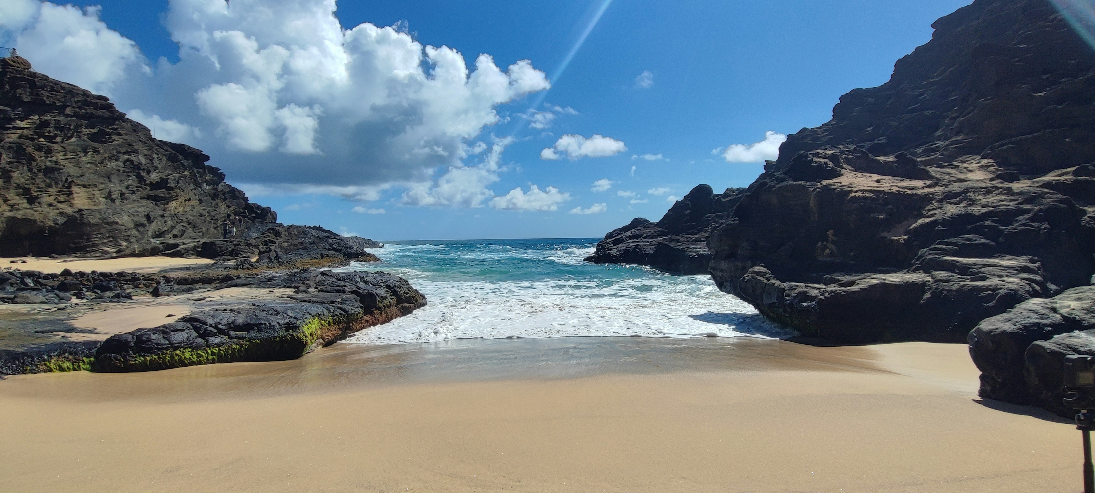 美丽的海滩景色，岩石悬崖和蓝天，波浪拍打海岸