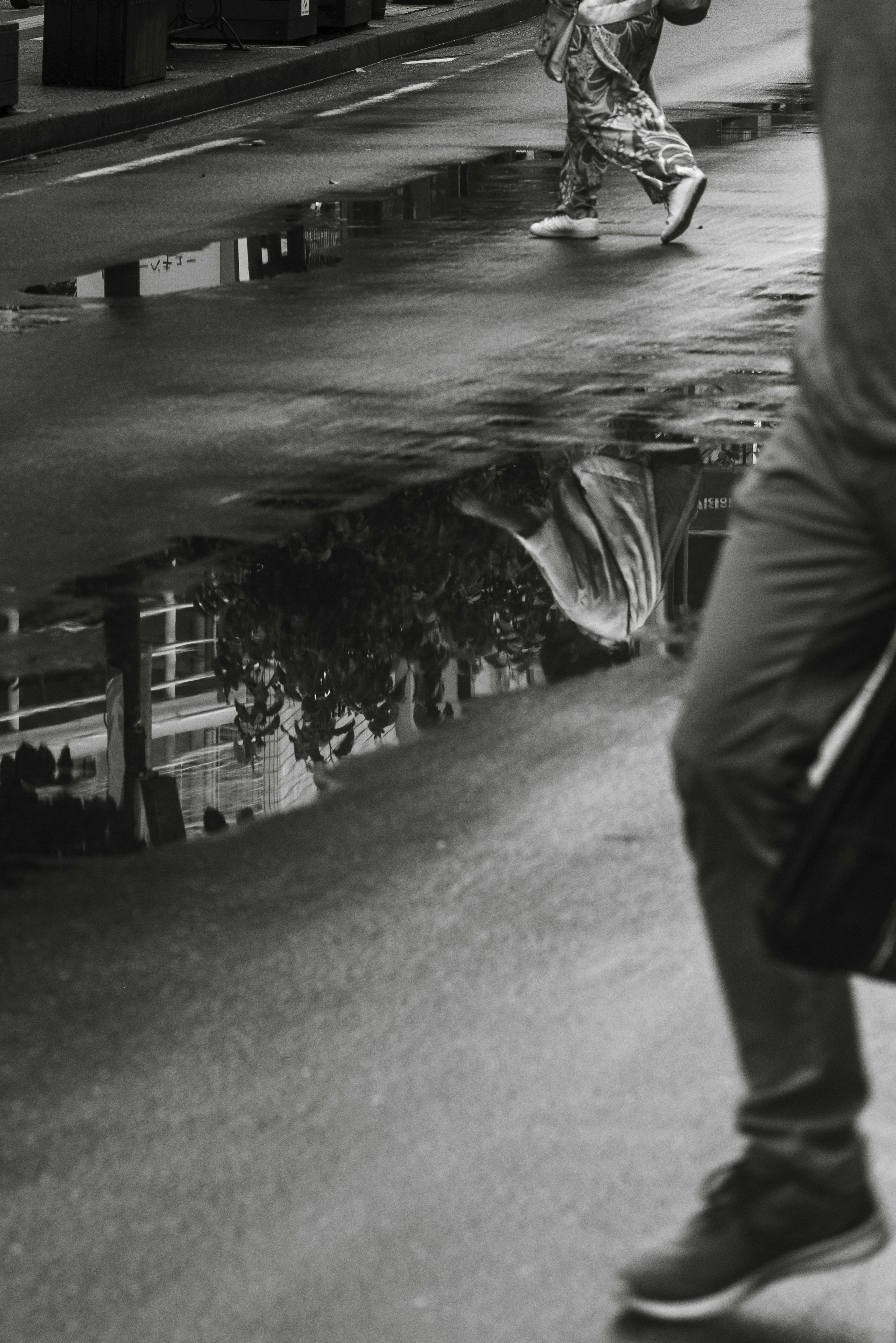 Black and white image showing reflections of people walking in the street