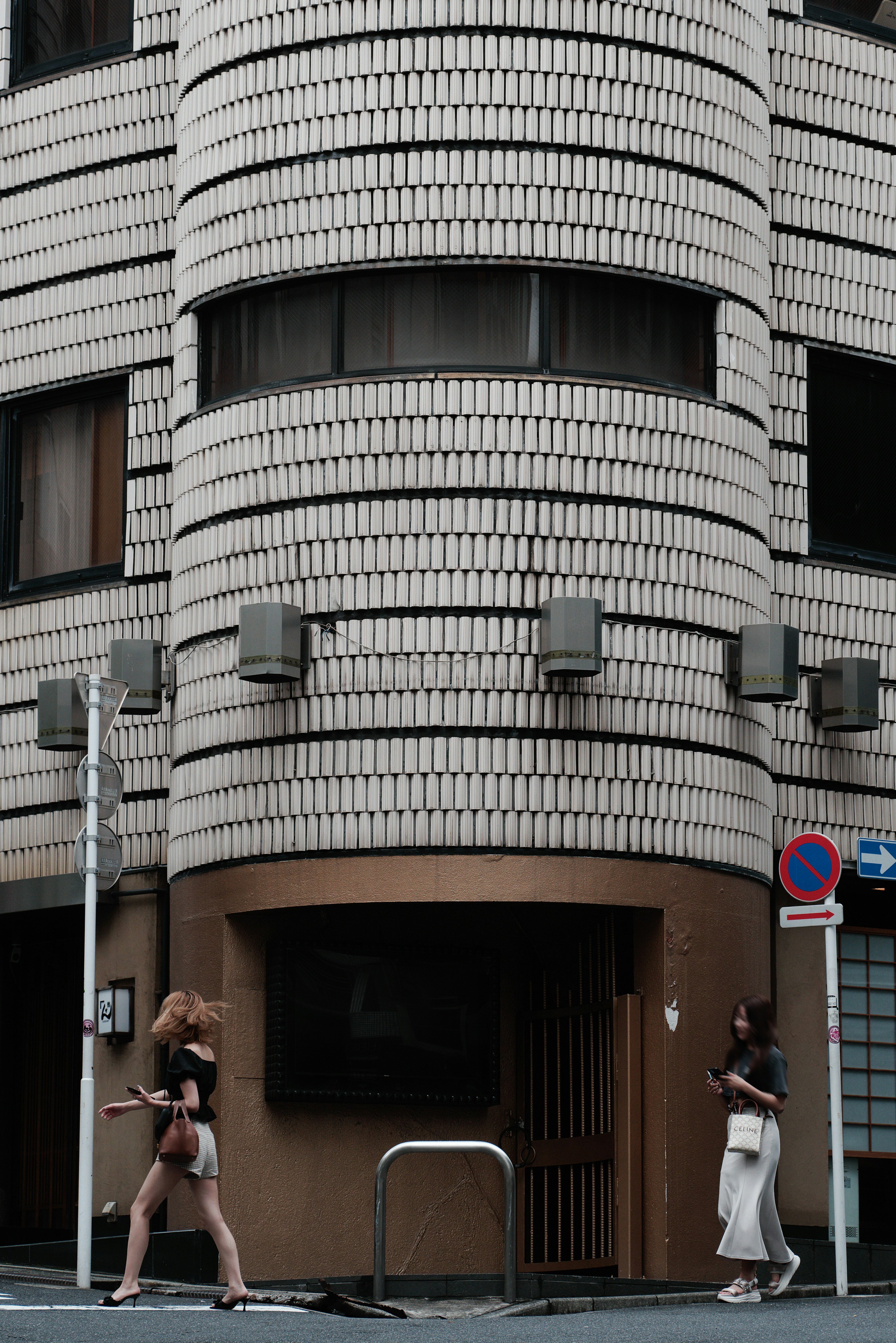 女性が街を歩く独特な建物の前の風景